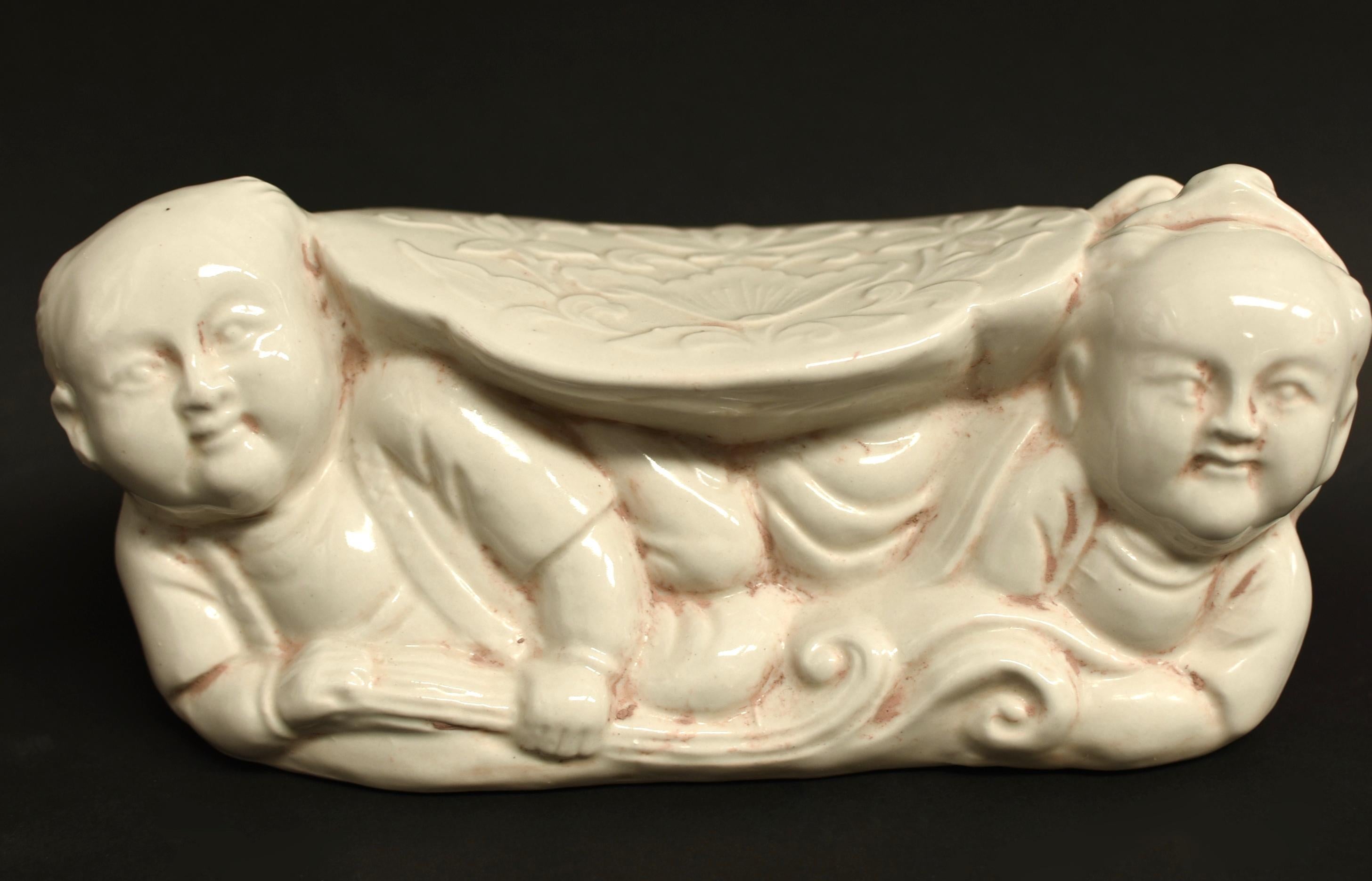 A song dynasty style ceramic pillow of the Ding kiln. The Ding kiln is one of the most important Song dynasty kilns. It produces milky white or beige glazed pieces that are favored for their simplicity and country grace. A pair of cherub boys raise