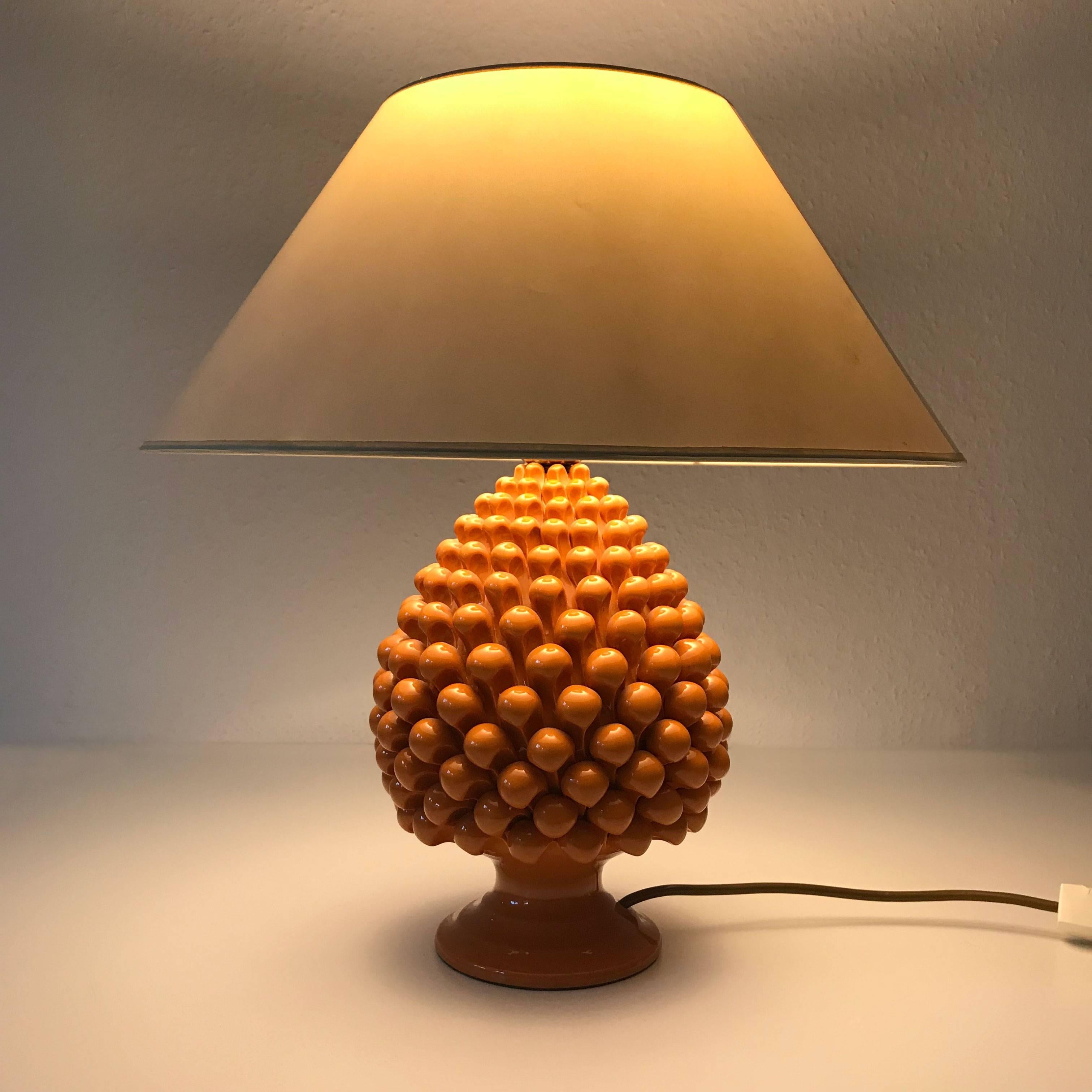 Highly decorative Mid-Century Modern table lamp with an orange ceramic base representing a pineapple. Designed probably by Marcello Fantoni, Italy, 1970s.

Executed in orange colored ceramic and fabric shade, the lamp needs 1 x E27 screw fit bulb