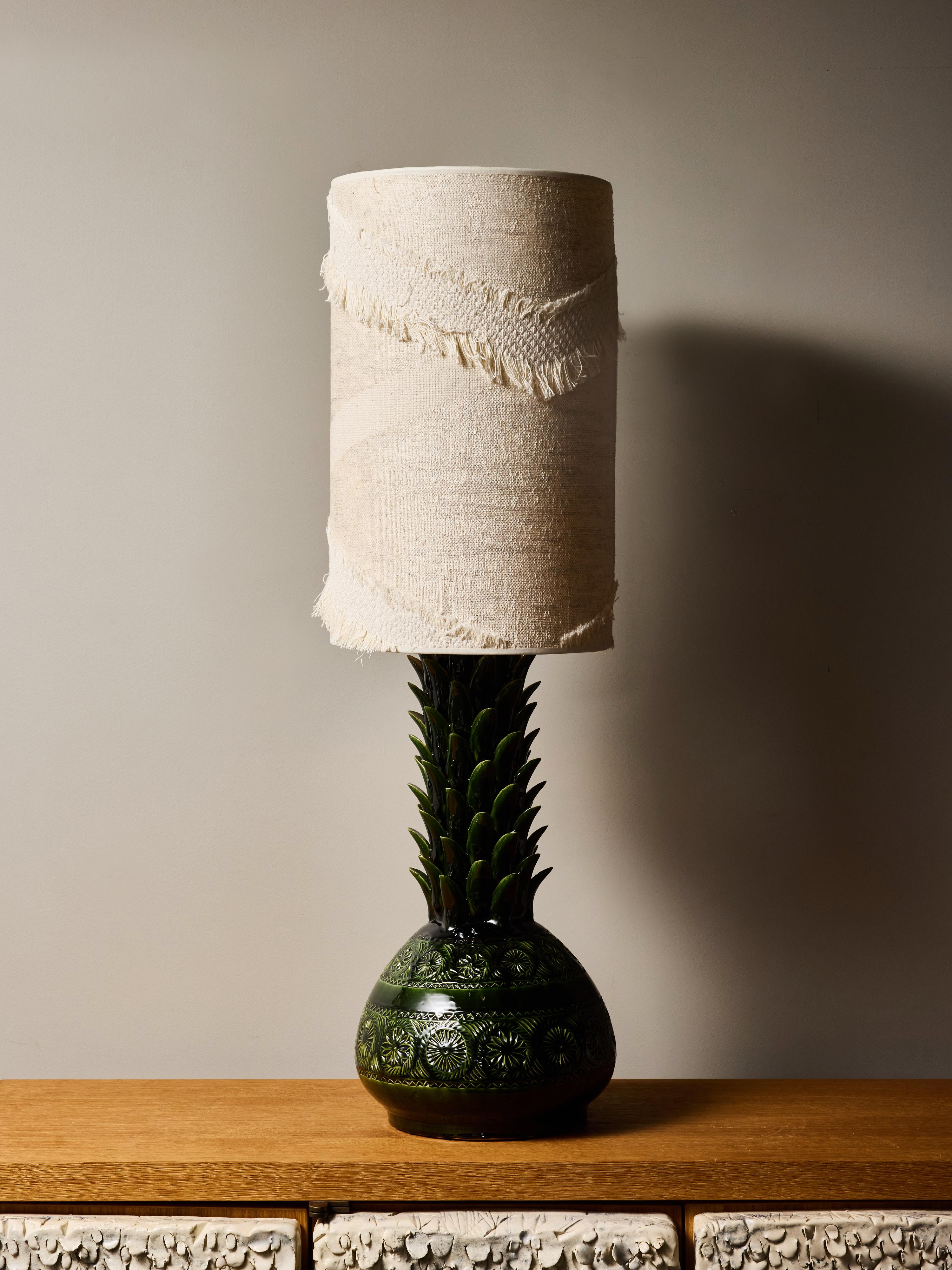 This striking Italian table lamp from the 1980s showcases a bold sculptural presence with its stylized pineapple silhouette and deep glaze.
Lush layers of glossy green leaves rise upward from a rounded, intricately patterned body, creating a rich