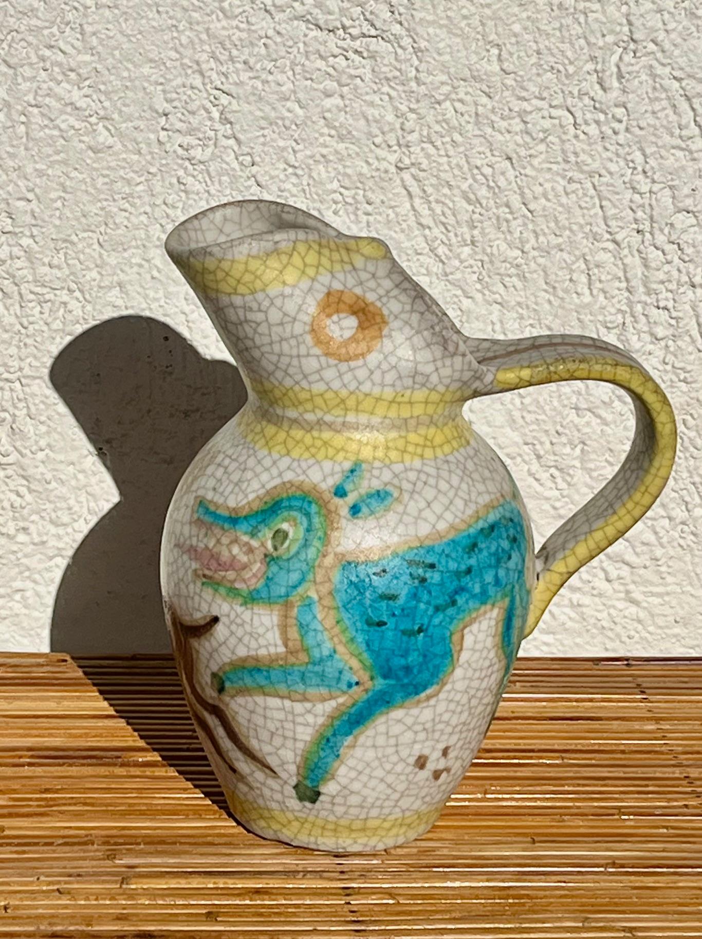 Beautiful ceramic pitcher by Guido Gambone. 
Rare decoration on the body of the pitcher depicting 2 running hounds, one blue, the other brown, on light background.
Glazed and cracked ceramic. 
Signed Gambone Italy, with donkey mark. 

Guido Gambone