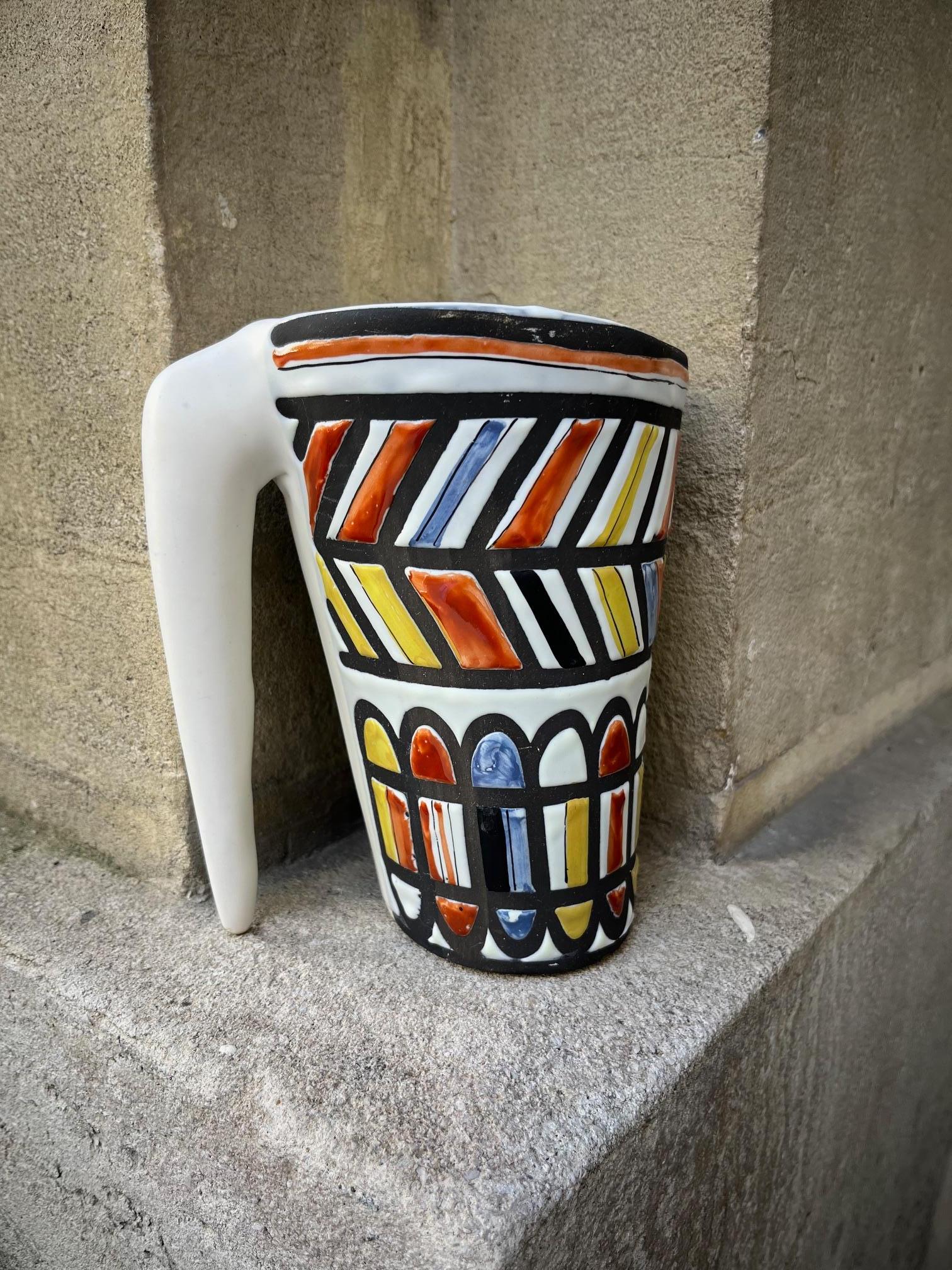  Ceramic pitcher by Roger Capron.
Glazed ceramic  with polychrome decoration in shades of red yellow, blue and black.  
This shape was referred to as 
