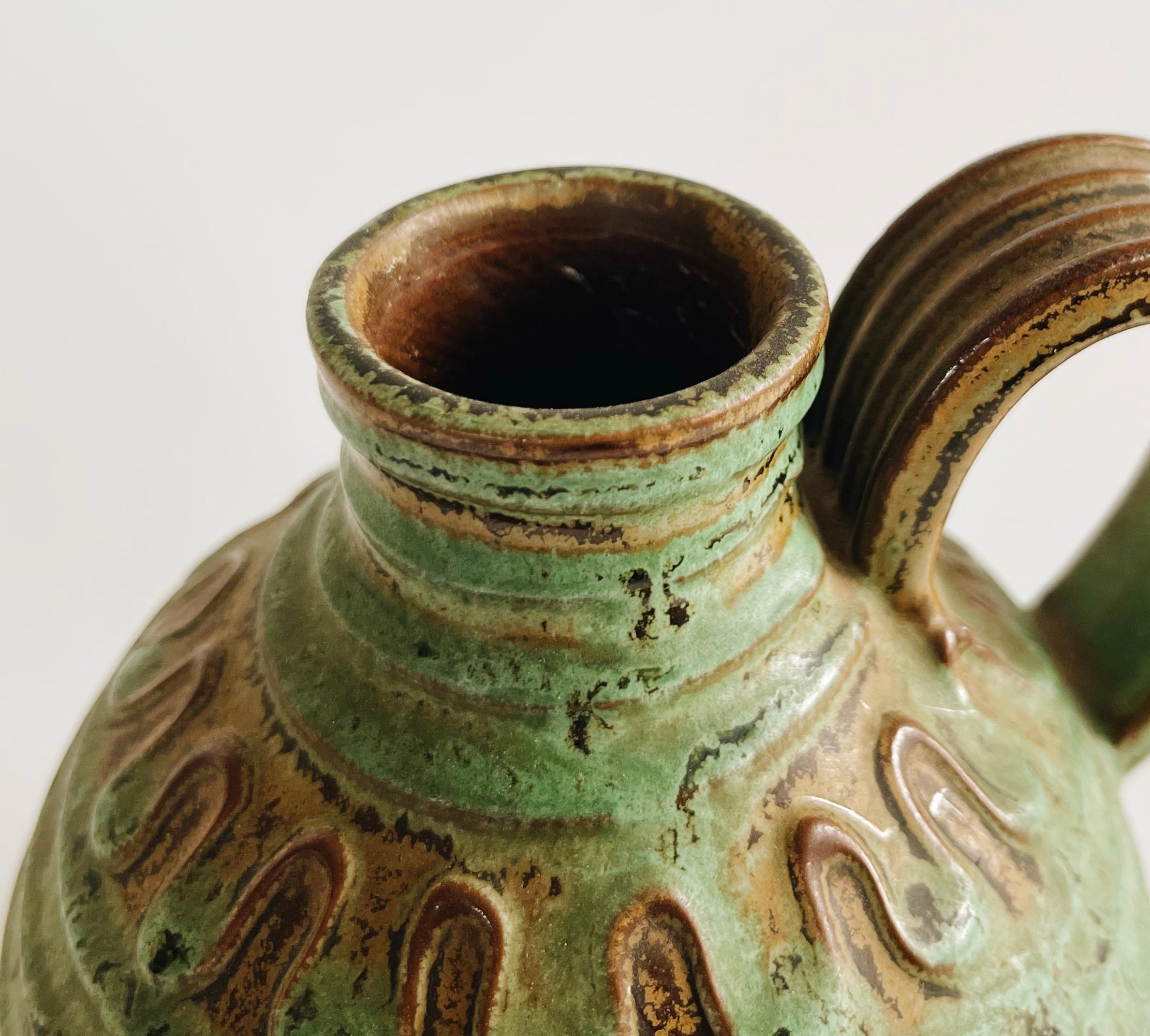 Questa brocca o vaso in terracotta, disegnata da Erik Mornils per Nittsjö Keramik negli anni '30, presenta un fascino rustico e tradizionale, caratteristico delle ceramiche scandinave dell'epoca.

La superficie è prevalentemente smaltata in una