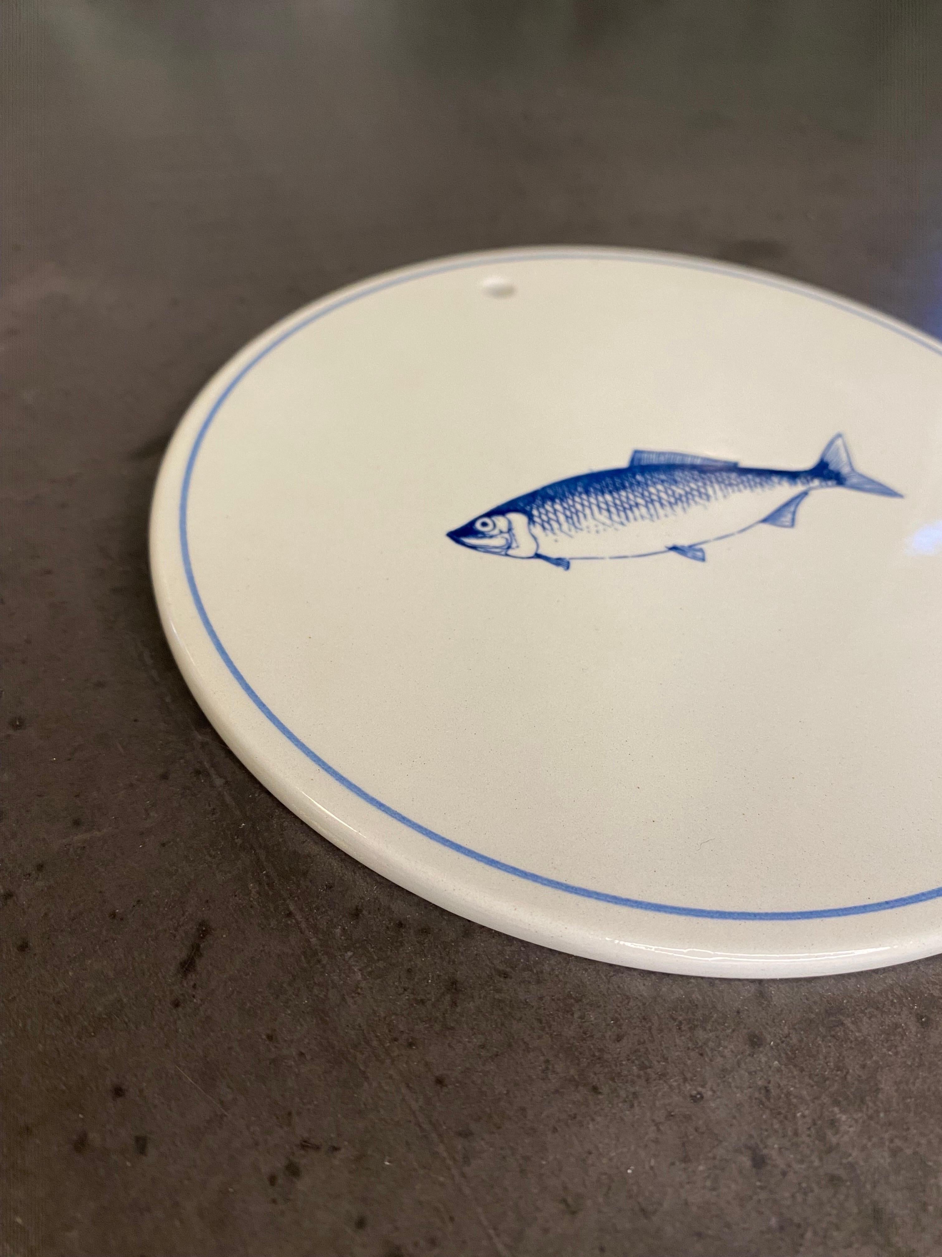 Ceramic wall or decorative plate with a single fish in light grey/blue colours. 
Can also be used as a bread plate
Measures: W: 15 cm, H: 0,6 mm

Have 16 pcs in stock.
Please let me know if you want to buy several pcs.

Good condition.
  