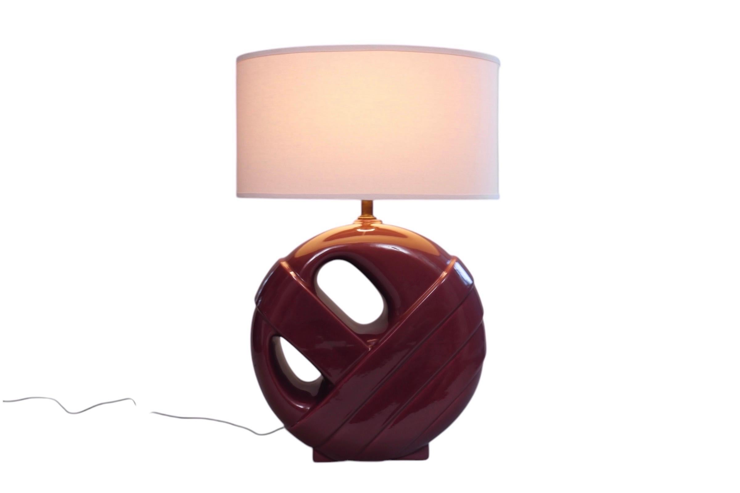 Une grande lampe de table postmoderne en céramique de couleur prune. Le vase est cylindrique avec deux sections percées, et est moulé pour donner l'impression qu'un côté est enveloppé. Livré avec un abat-jour ovale en forme de tambour. La lampe