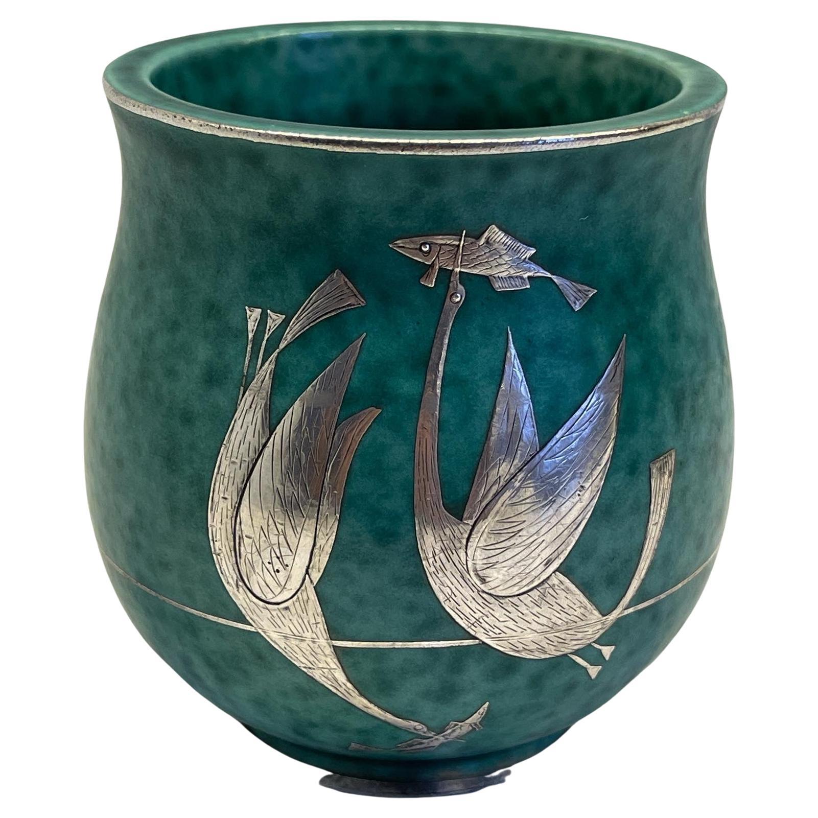 A pot in ceramic with hand made silver inlay from the 1930s Argenta collection made by Wilhelm Kåge for Gustavsberg, signature underneath.
 The now iconic argenta stoneware collection, with its green glaze and silver decoration, is one of wilhelm
