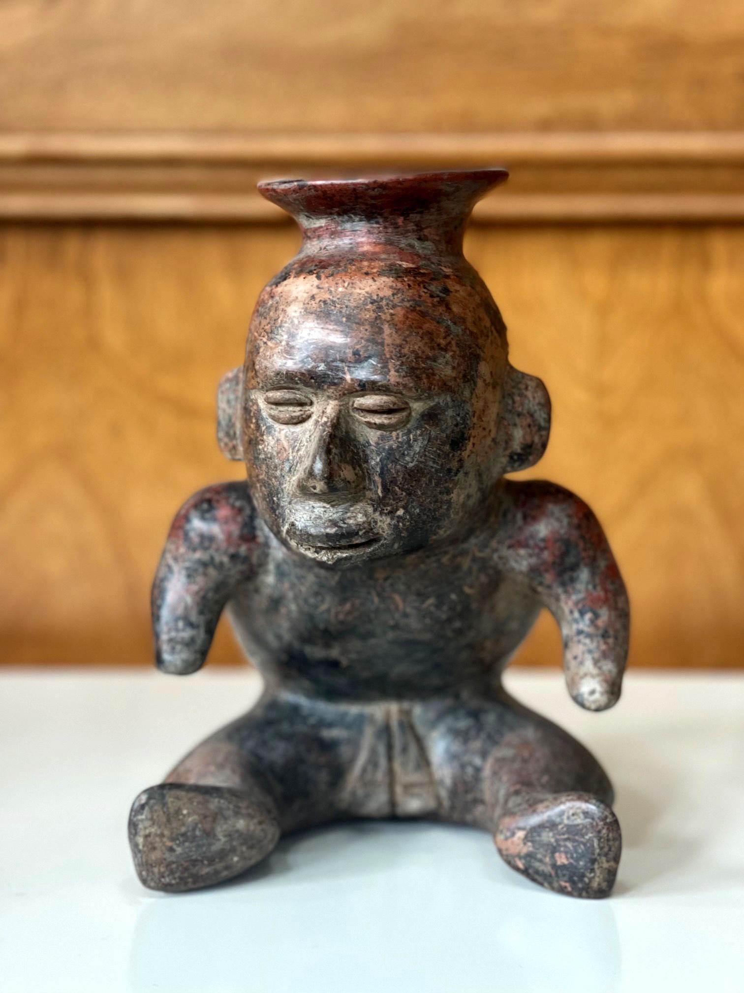 A pre-Columbian figural vessel from West Mexico Colima culture (circa 300BC-400AD). Made of molded clay, the stoneware vessel depicts a seated hunchback woman with truncated style arms and opening sprout on top of the head. The highly stylized