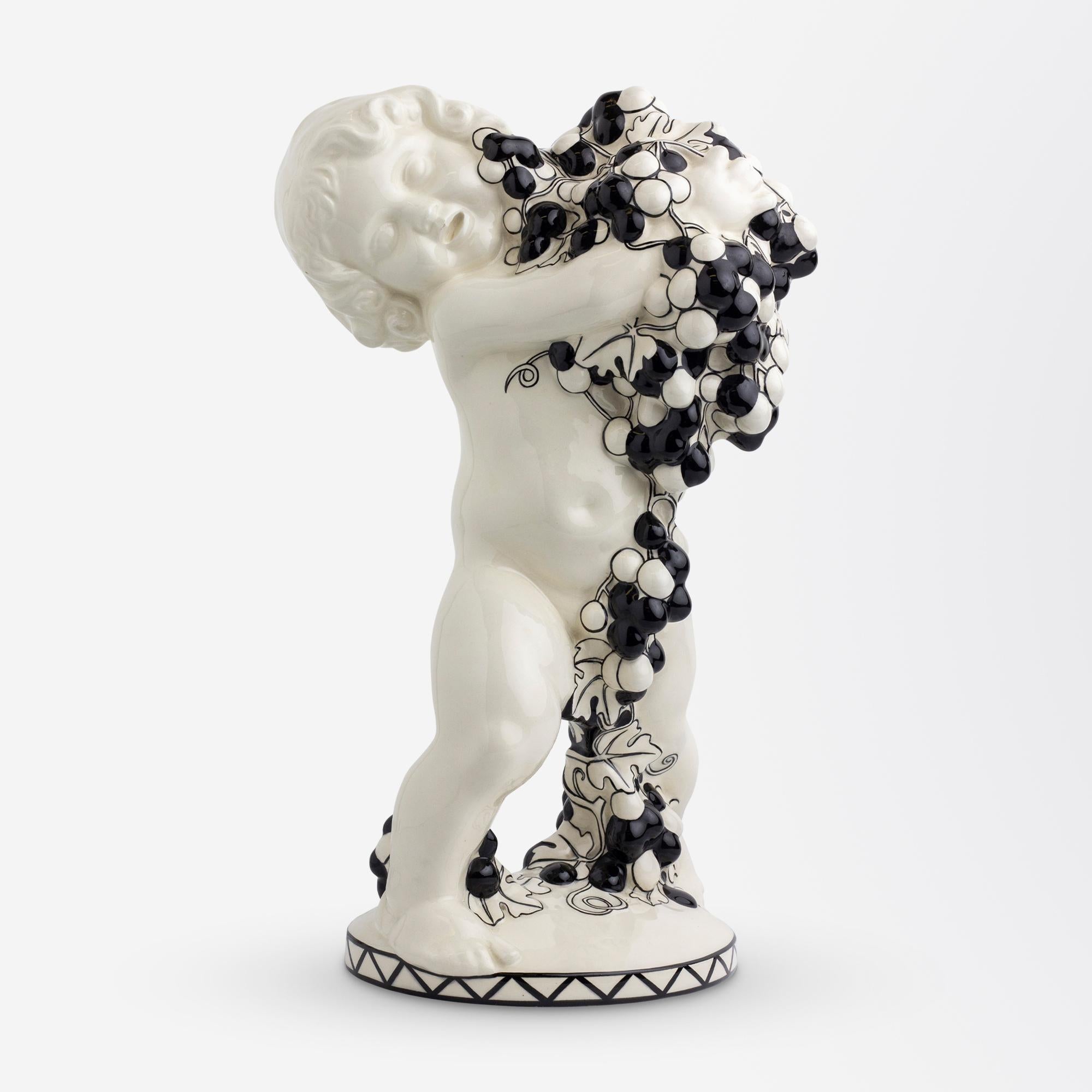 A large and rare ceramic monochromatic putto holding grapes (Autumn from 