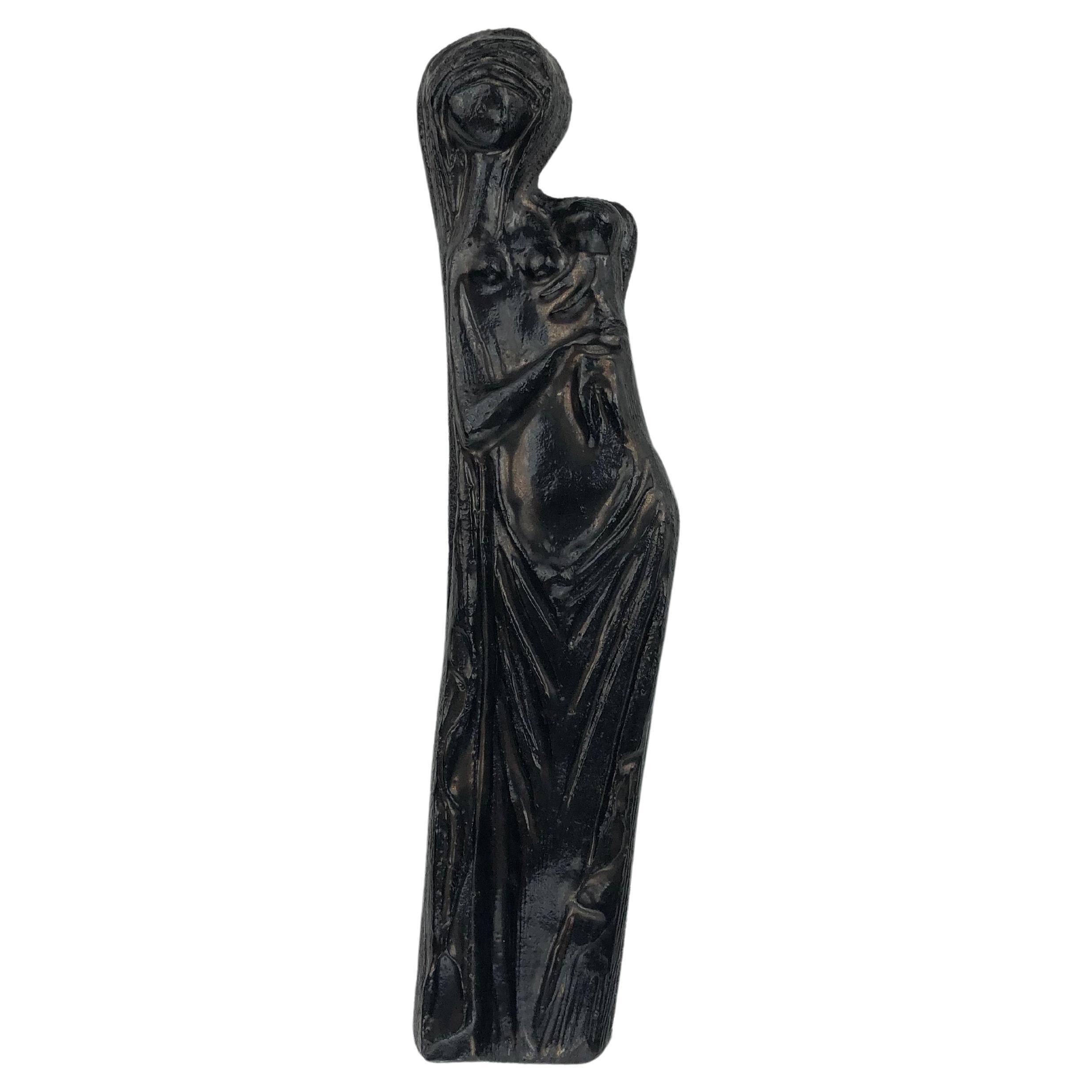Die schwarze Keramik-Jungfrau Maria ist mit dezent irisierenden Brauntönen verziert. Dieses Keramikkreuz besticht durch eine Mischung aus erdiger Wärme und modernem Design. Der Glanz der matten Glasur und die subtilen Gesichtsausdrücke verleihen der