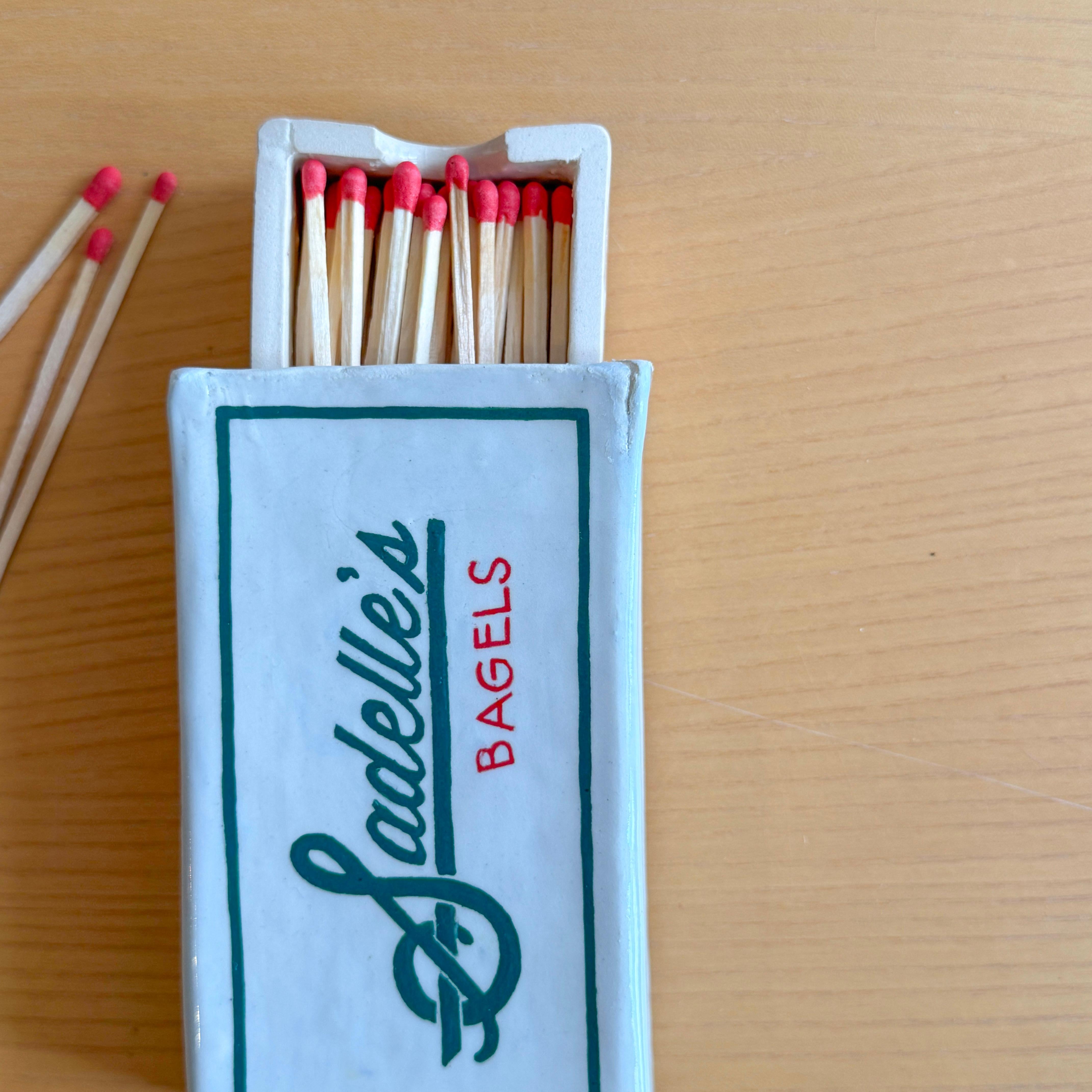 La série Matchbox est composée de boîtes d'environ 4 x 6 pouces qui font directement référence à des institutions emblématiques de New York. Ces boîtes sont munies d'inserts coulissants remplis d'allumettes surdimensionnées, environ 20 à 30 par