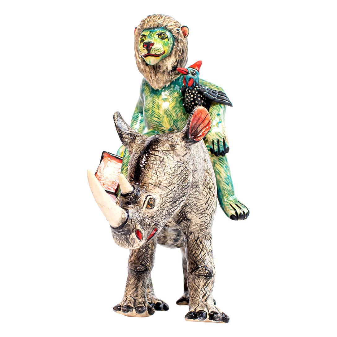 Die Keramikskulptur Blaues Nashorn und Löwe von Zimele Ceramics ist ein fesselndes Stück aus der Kollektion African Circus, die von Zimele Original Ceramics entworfen und durch die Kunstfertigkeit von Petros und Matrinah zum Leben erweckt wurde. Mit