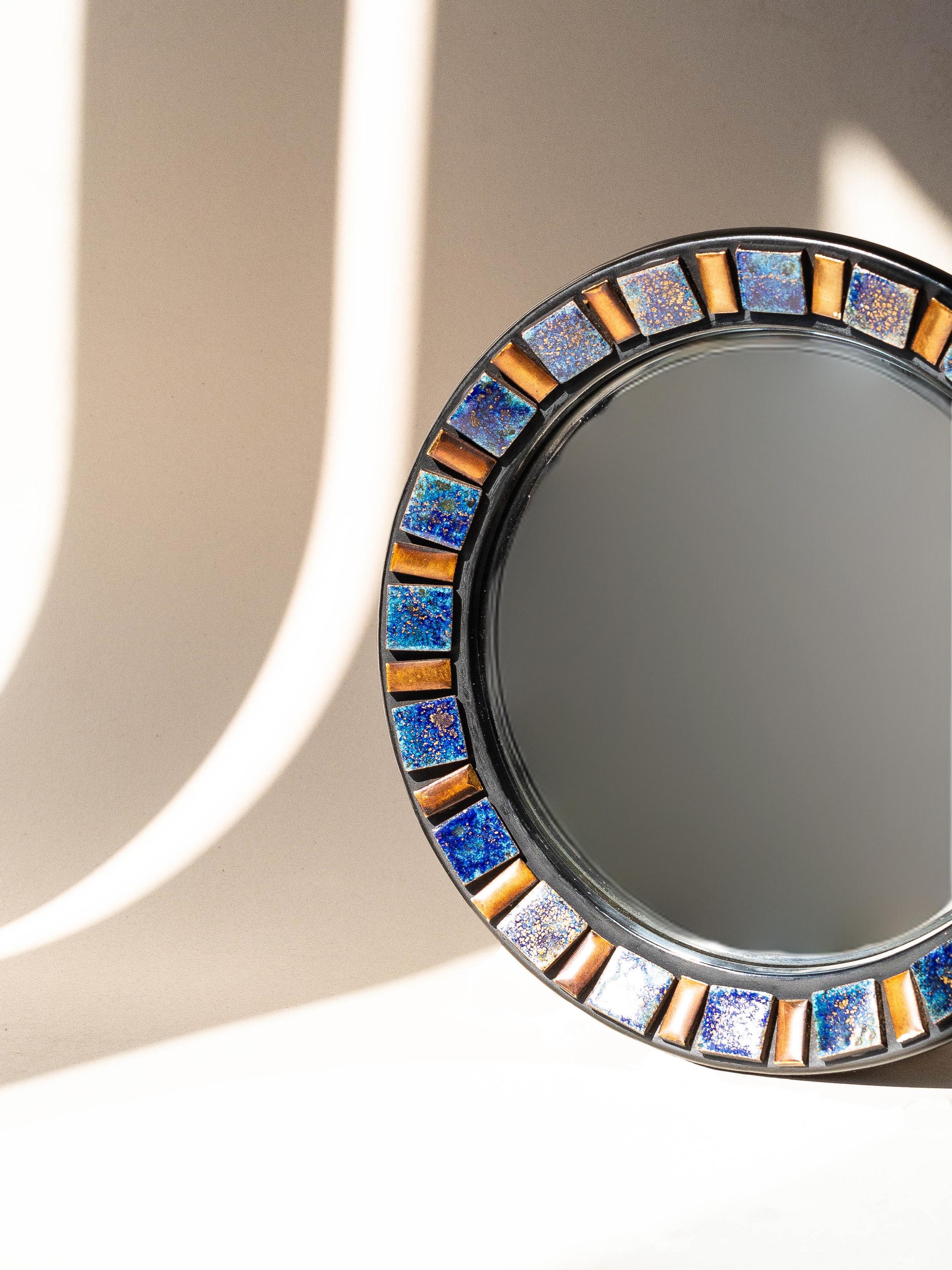 Ceramic Round Wall Mirror, Convex Glass, Belgium 1970s.

The mirror frame is made of black lacquered wood and is adorned with glazed earthenware in blue and gold. 

The ceramic squares and rectangles come in two different shades : blue with golden