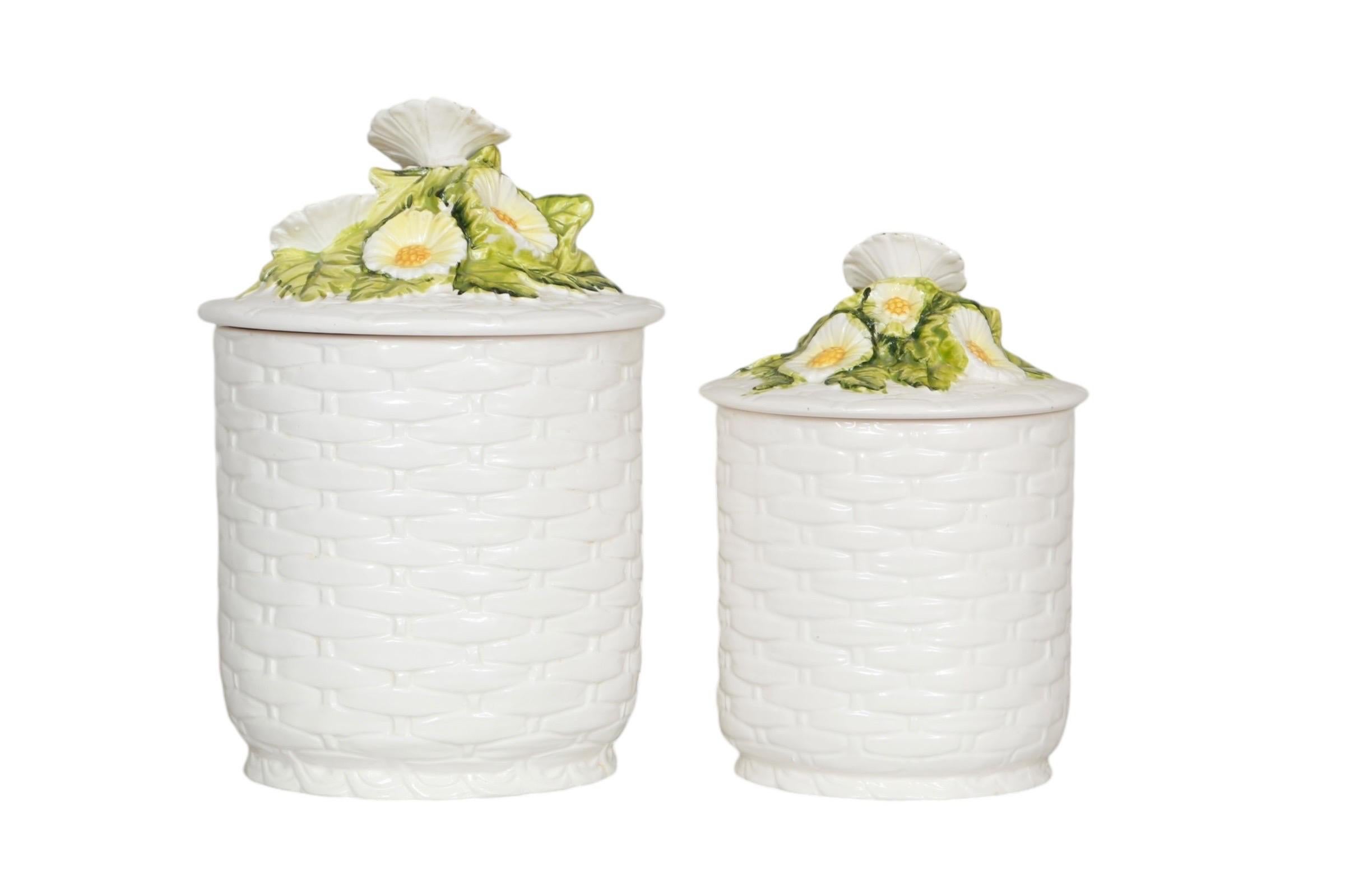 A set of two 1970’s ‘Rustic Daisy’ ceramic canisters imported from Japan by Lefton. White bases are pressed to give a woven basket look, and lids lift off with a cluster of white daisies over green leaves as handles. Marked and signed underneath “C