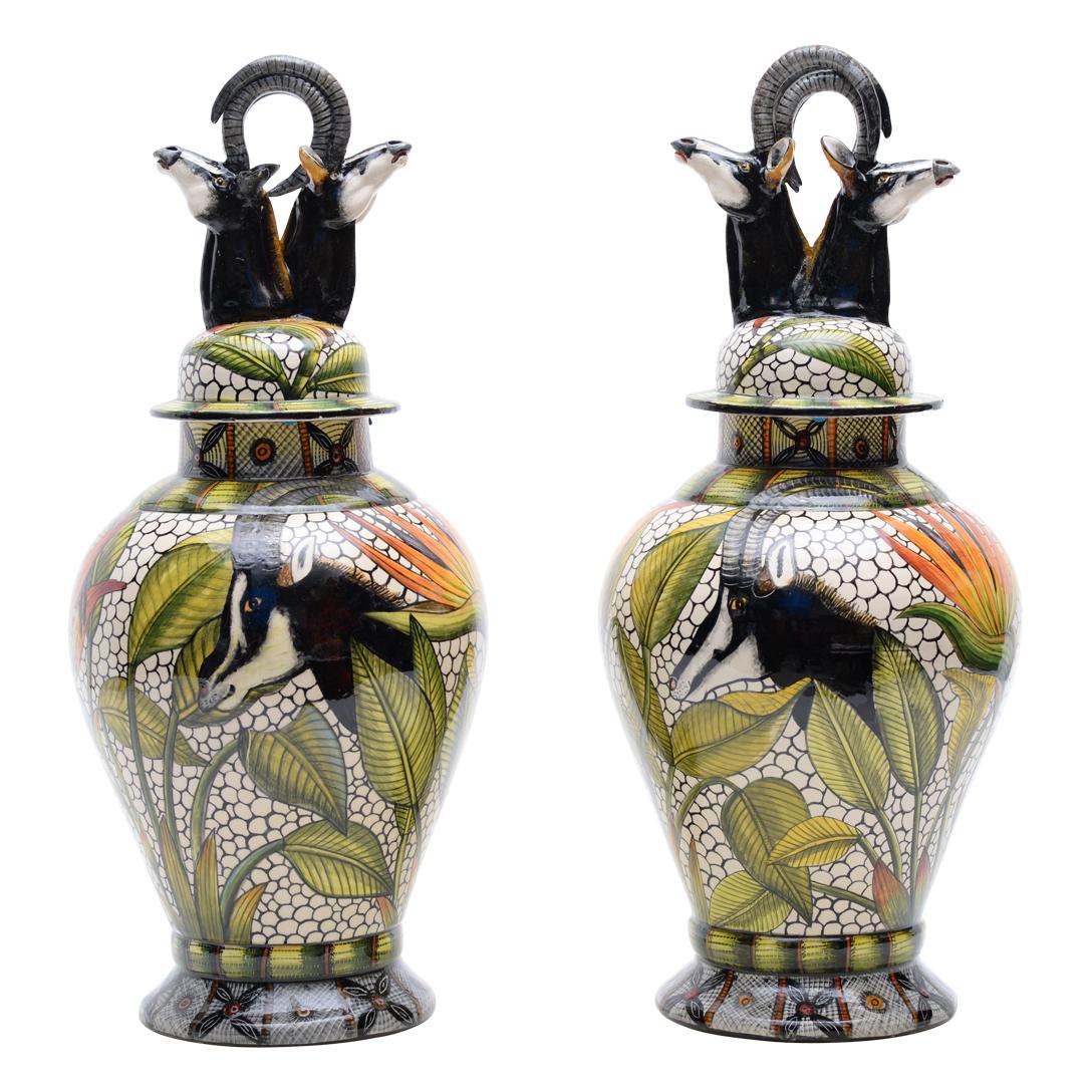 Scolpita a mano da Thabo & George e dipinta a mano da Wiseman Ndlovu presso la Wiseman Ceramics in Sudafrica, questa coppia di urne di zibellino in ceramica misura 19 pollici di altezza e 8 pollici di lunghezza e larghezza. Disegnate da Wiseman