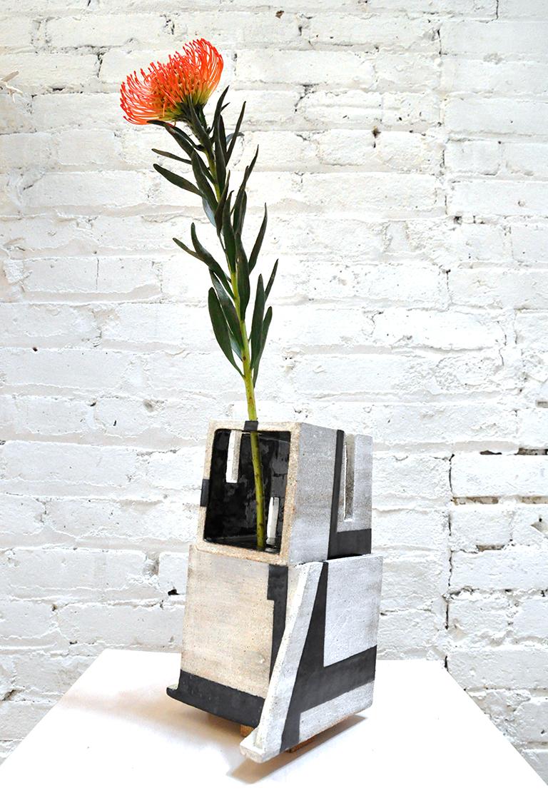 This ceramic sculptural vessel by Kathryn Robinson-Millen is hand built in stoneware using an elaborate, geometric slab construction. The piece is reduction fired.
The interior is painted with a black terra sigillata and glazed to seal (the vessel