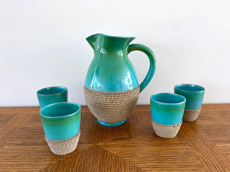 Fantastic ceramic set with carafe pitcher and four glasses by Ugo Zaccagnini
Beautiful turquoise colored glaze wrapped in rope 
Italy, 1960s.
 