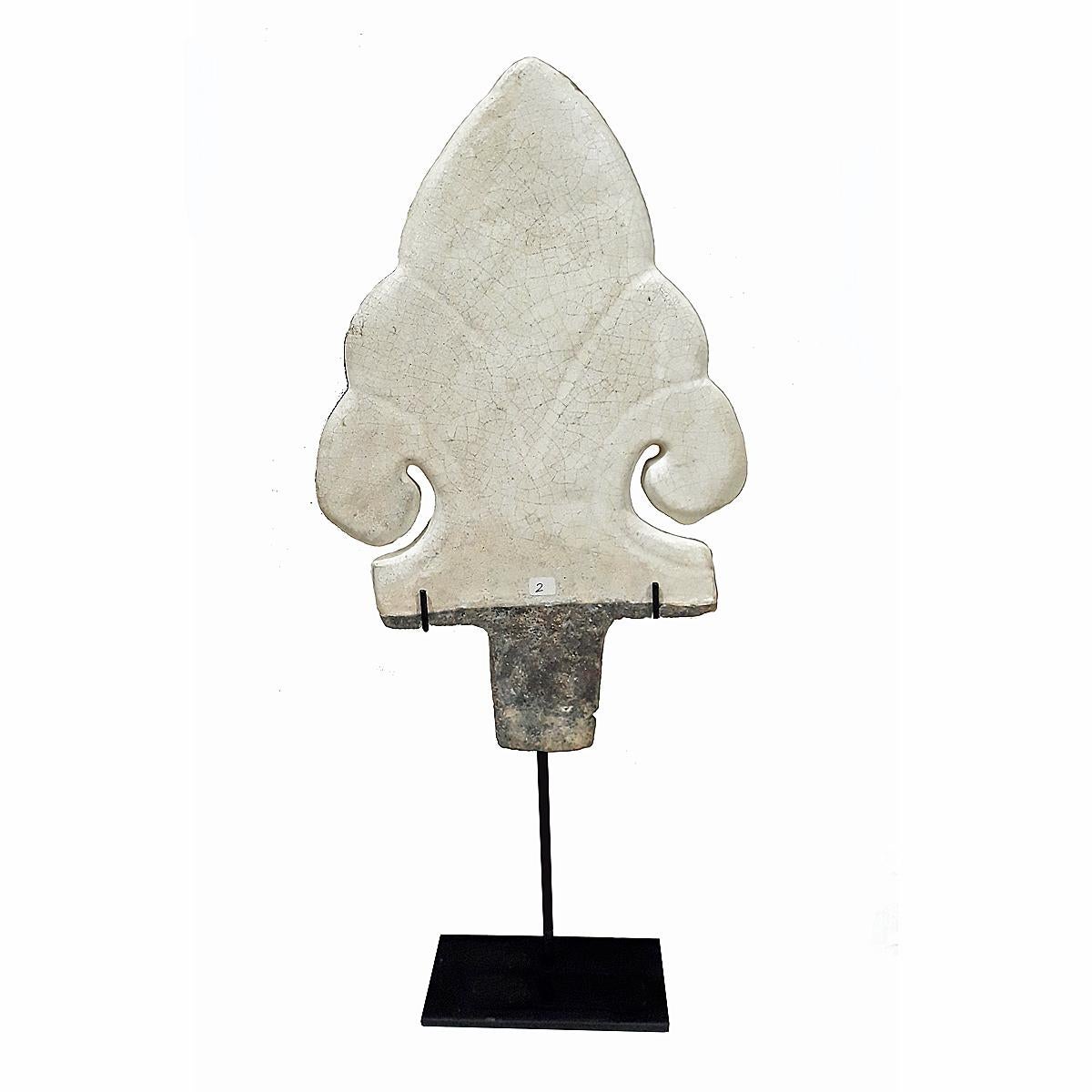 A ceramic shield-shaped architectural detail from Thailand, 500 years old. 
Hand-crafted in the old kilns of Sukhothai, one of the main historic centers of Thai ceramics. Glazed in white with the typical Celadon-style crackled finish. Mounted on a