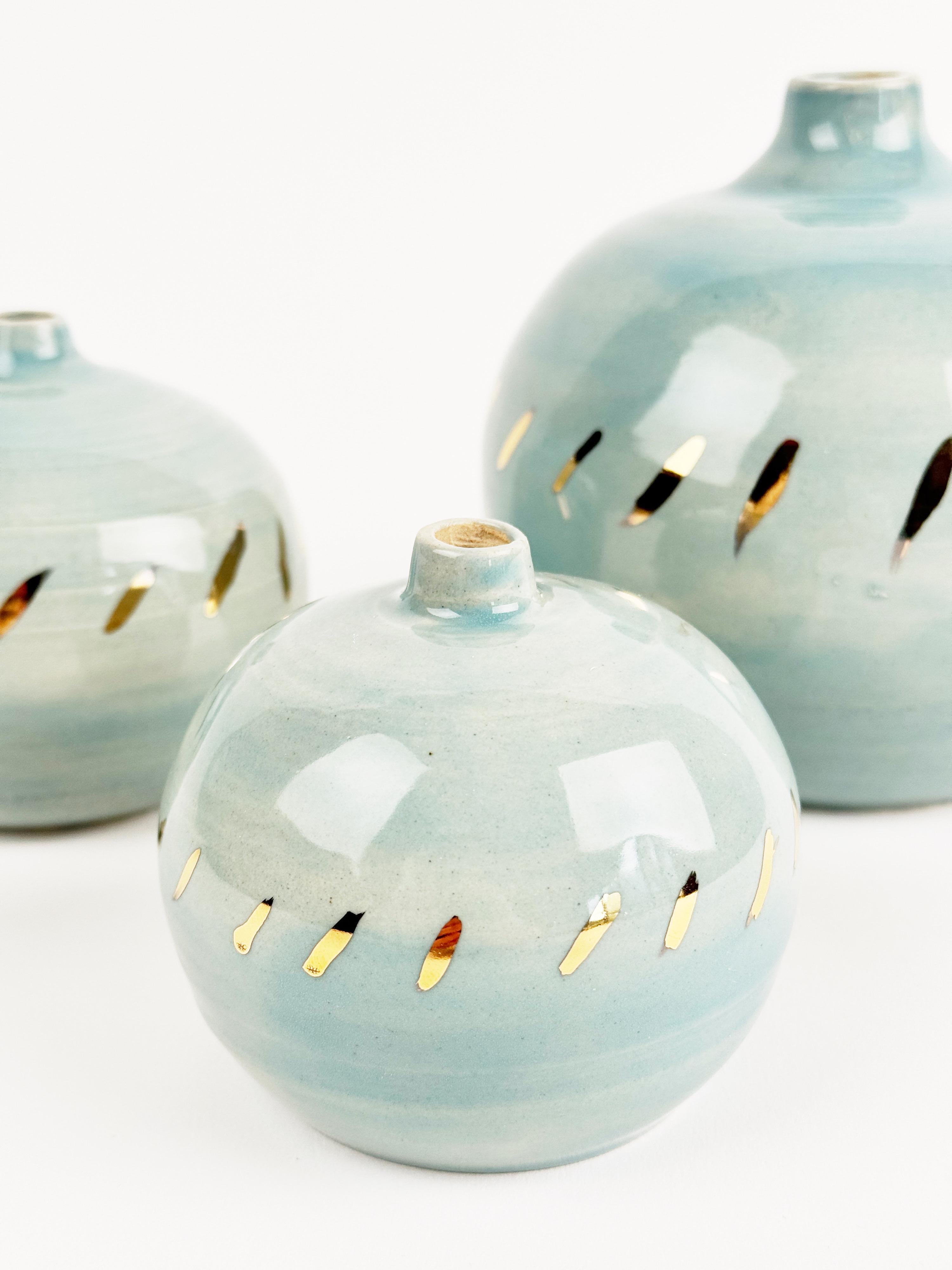 Dieses exklusive Set aus handgefertigten Keramikkugeln ist in einem durchscheinenden Celadon-Finish glasiert und weist präzisionsgeschnittene Öffnungen auf, die ein leuchtendes, mit 12% flüssigem Gold beschichtetes Inneres offenbaren. Jede
