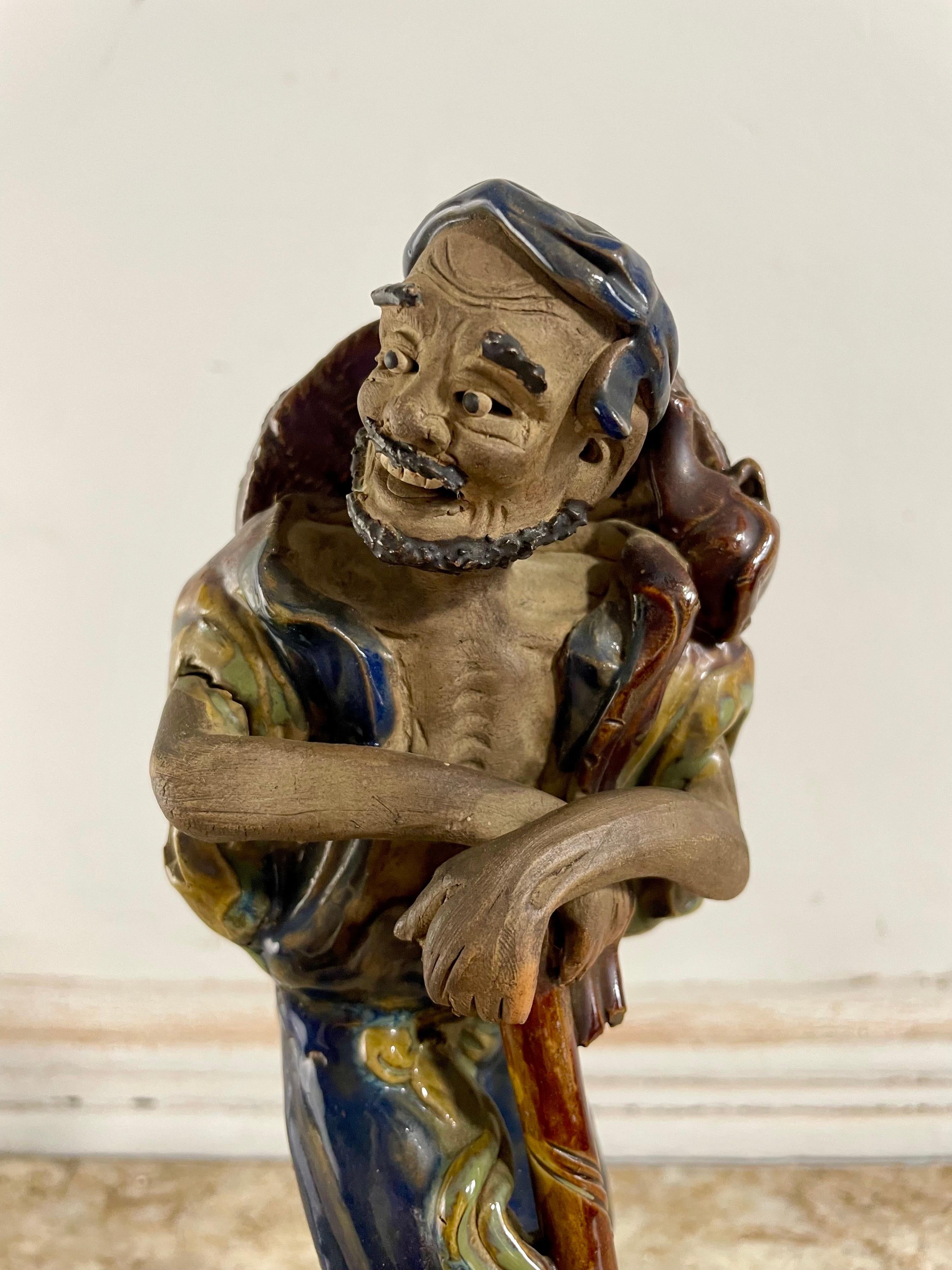 Ceramic statuette from Shiwan partially glazed in yellow and blue representing Li Tieguai standing leaning on a stick, his hat behind his back.

Under the foot is still the piece of an old sale label from a XIXth or early XXth shop.
