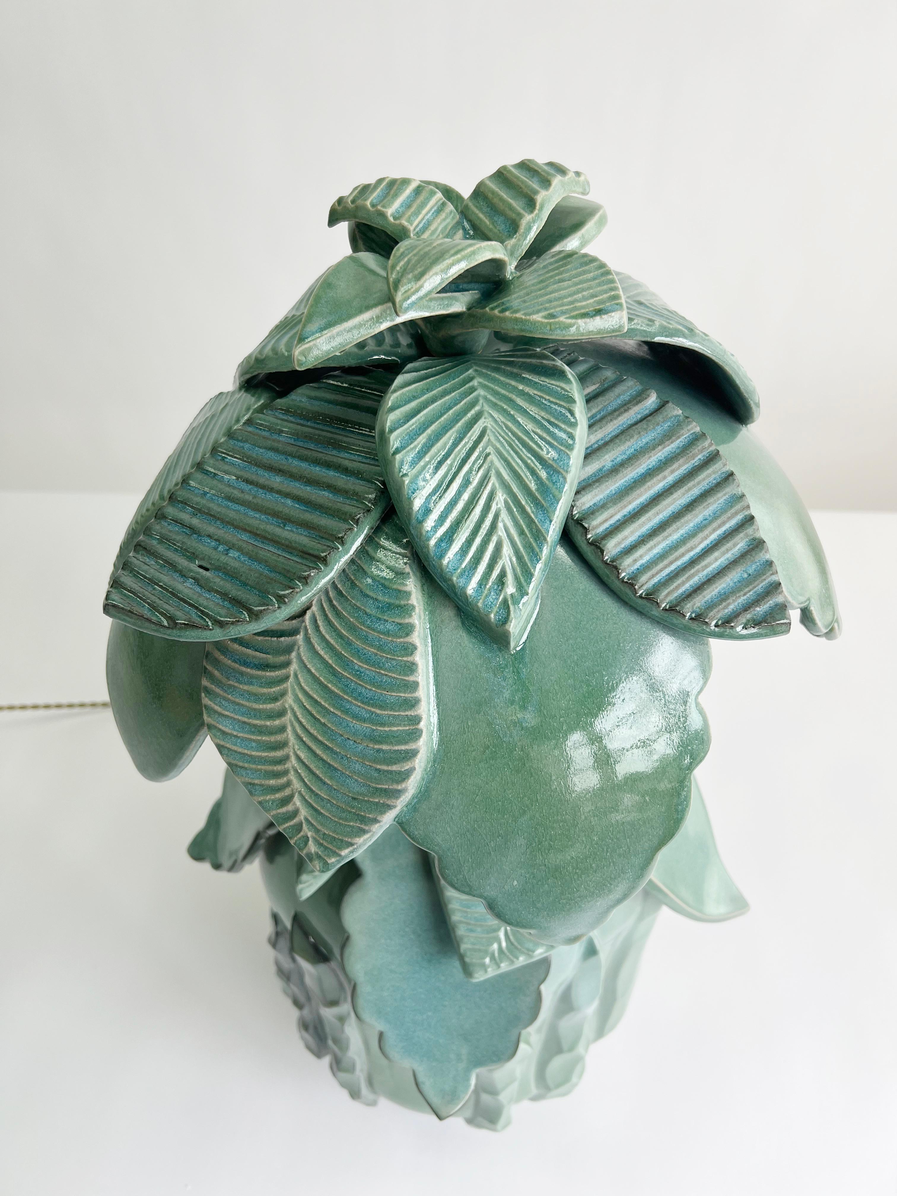 Inspired by architectural details from southern Spain, this ceramic stoneware lamp features hand-sculpted and carved, cascading leaves forming the finial, lamp body and lamp shade. The cascading leaf design continues atop the substantial lamp body.