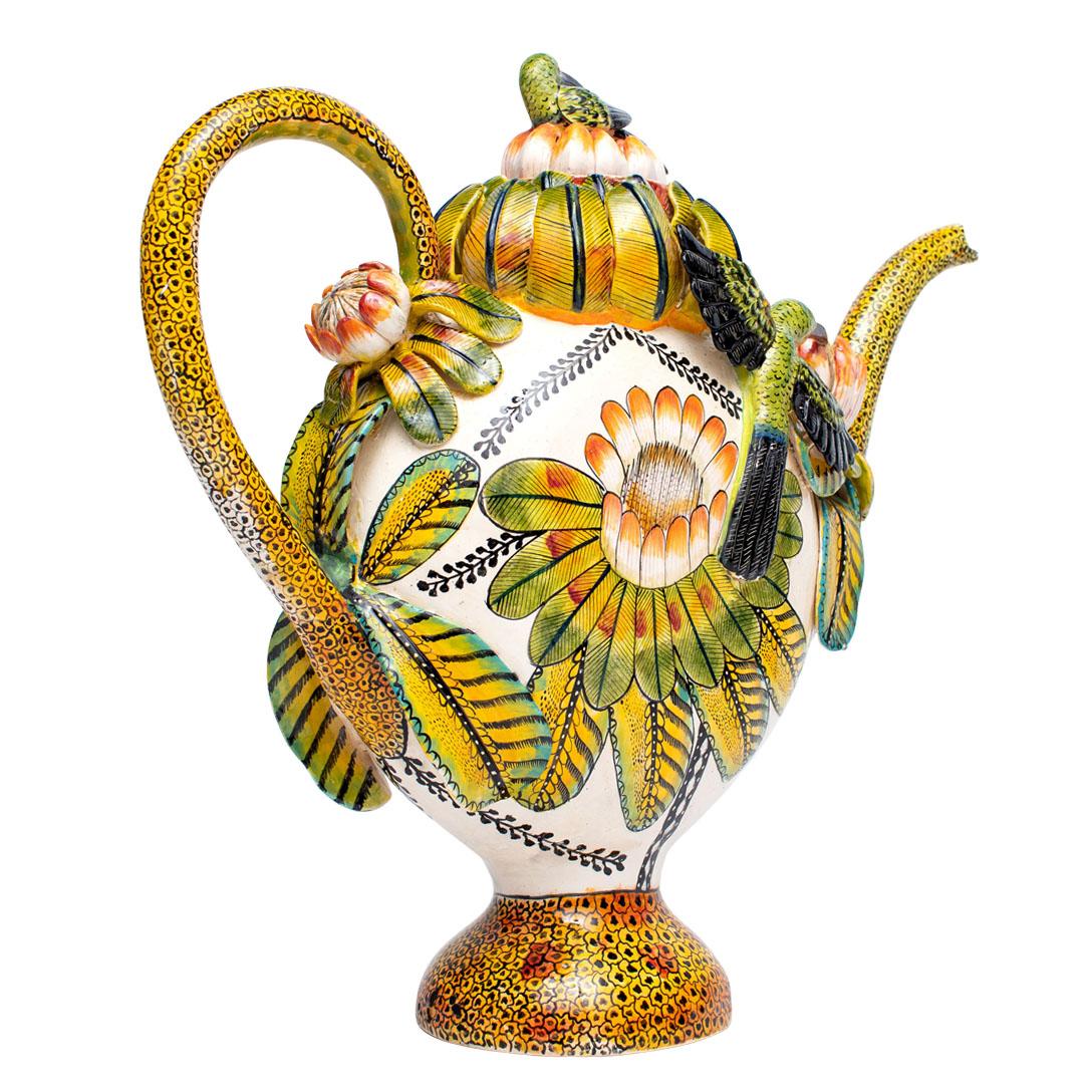 Crafted at Wiseman Ceramics in South Africa, this ceramic Sun bird teapot stands 16 inches high, with dimensions of 19 inches in length and 7 inches in width. Hand-sculpted by George & Thabo and hand-painted by Riya, this masterpiece reflects