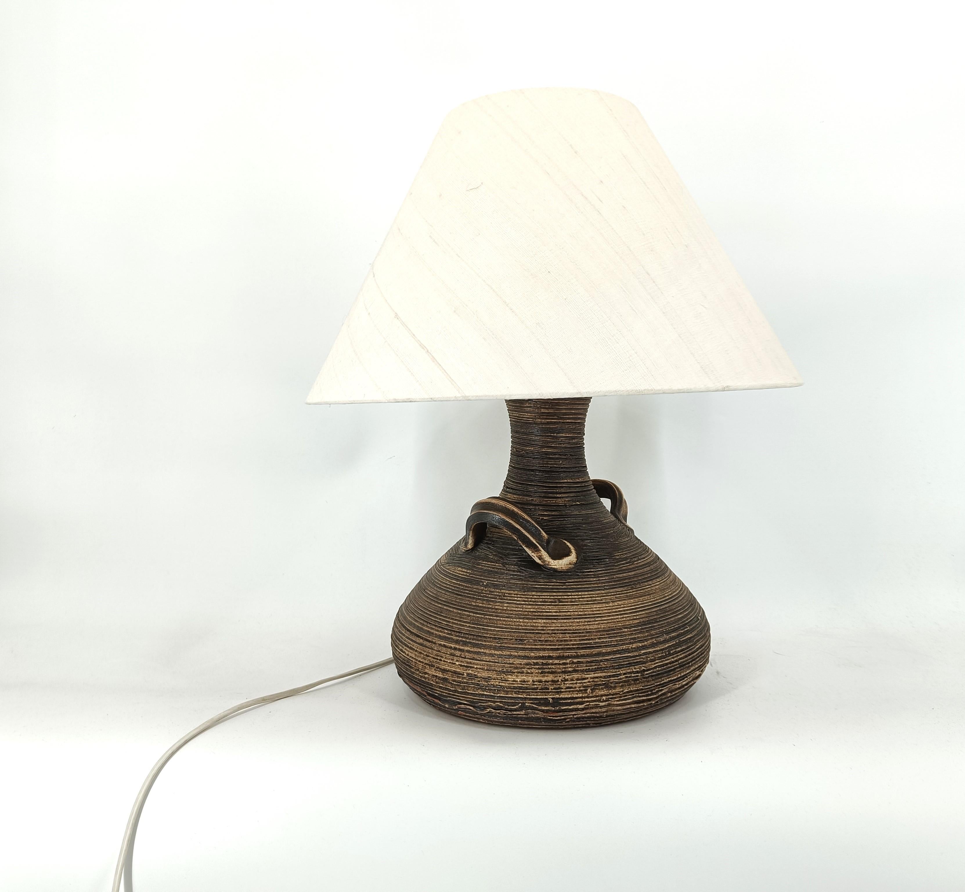 Robusta lámpara de sobremesa con base de cerámica en forma de jarrón y su original pantalla de tela beige.

Diseño atractivo.

Luz ambiental cálida

Probado y listo para usar con una bombilla E27.

Años 60 - Alemania

Dimensiones:
Altura: 62