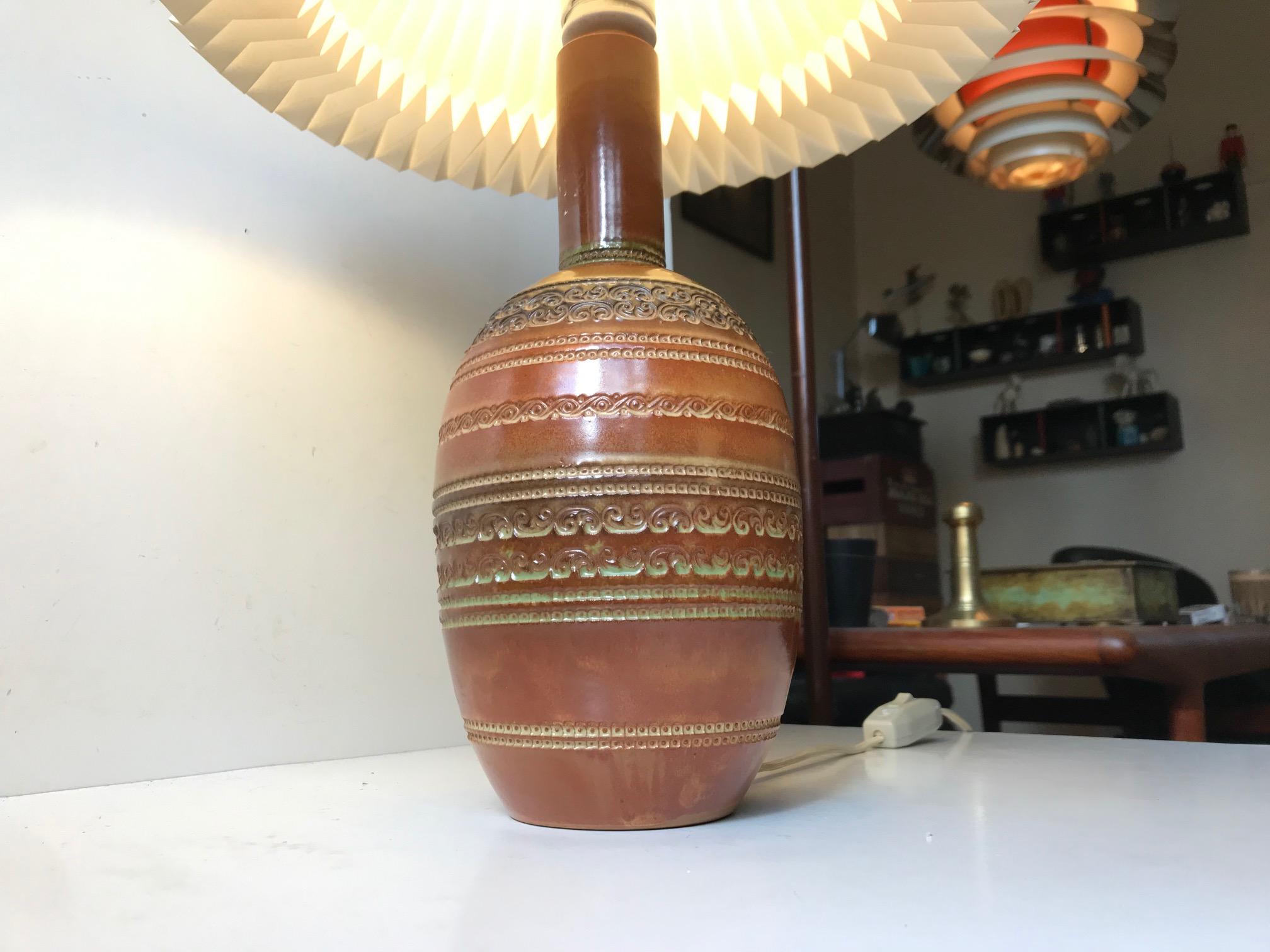 A tall gourd shaped ceramic table lamp with relief/ribbings and applied caramel and olive green glaze. It was designed by Aldo Londi and manufactured by Bitossi in Italy during the 1960s. It is signed/marked Italy to the inside of the base. The