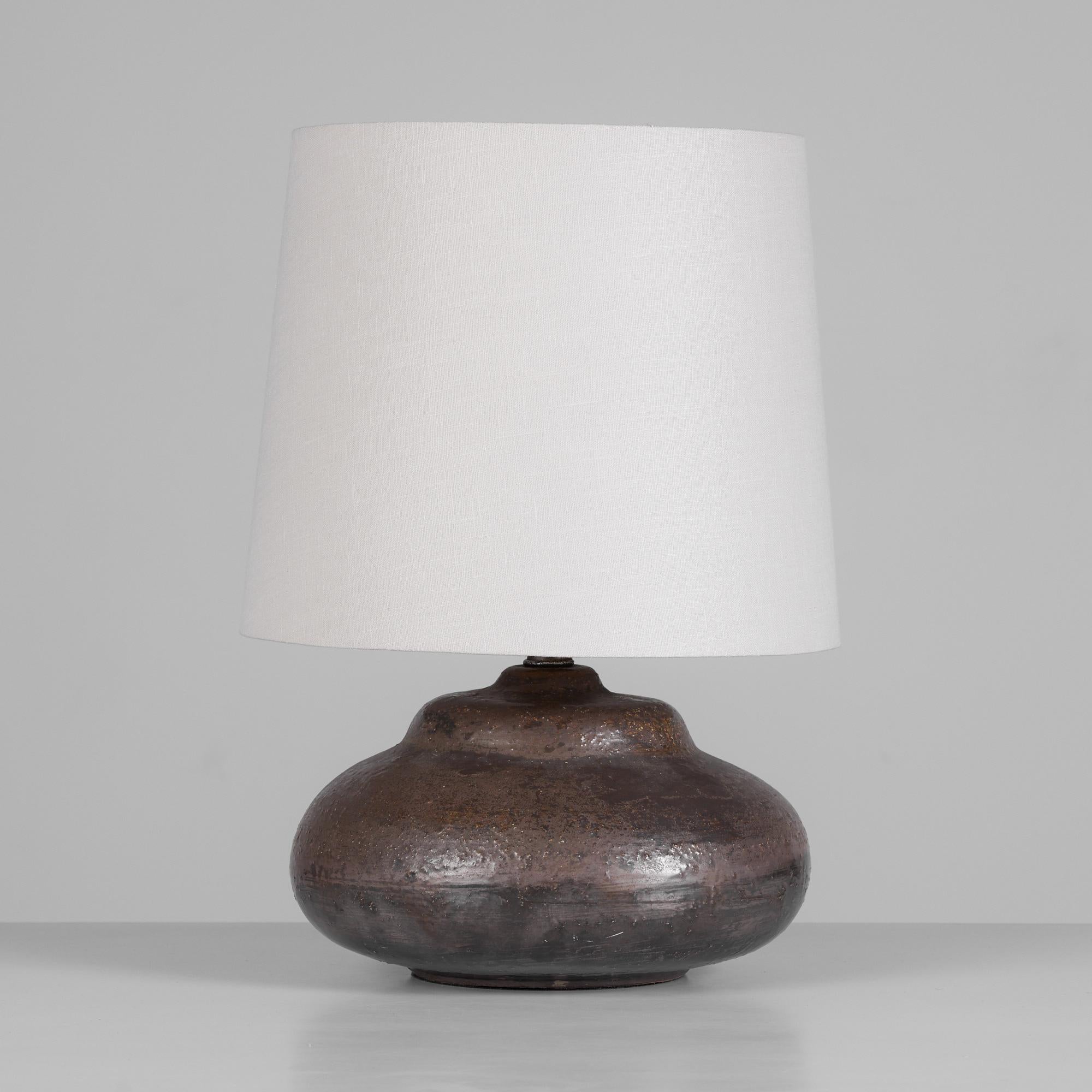 This ceramic table lamp by Aldo Londi for Bitossi, Italy, c.1960s features a stout, tiered curvaceous base that is finished in a brown and 