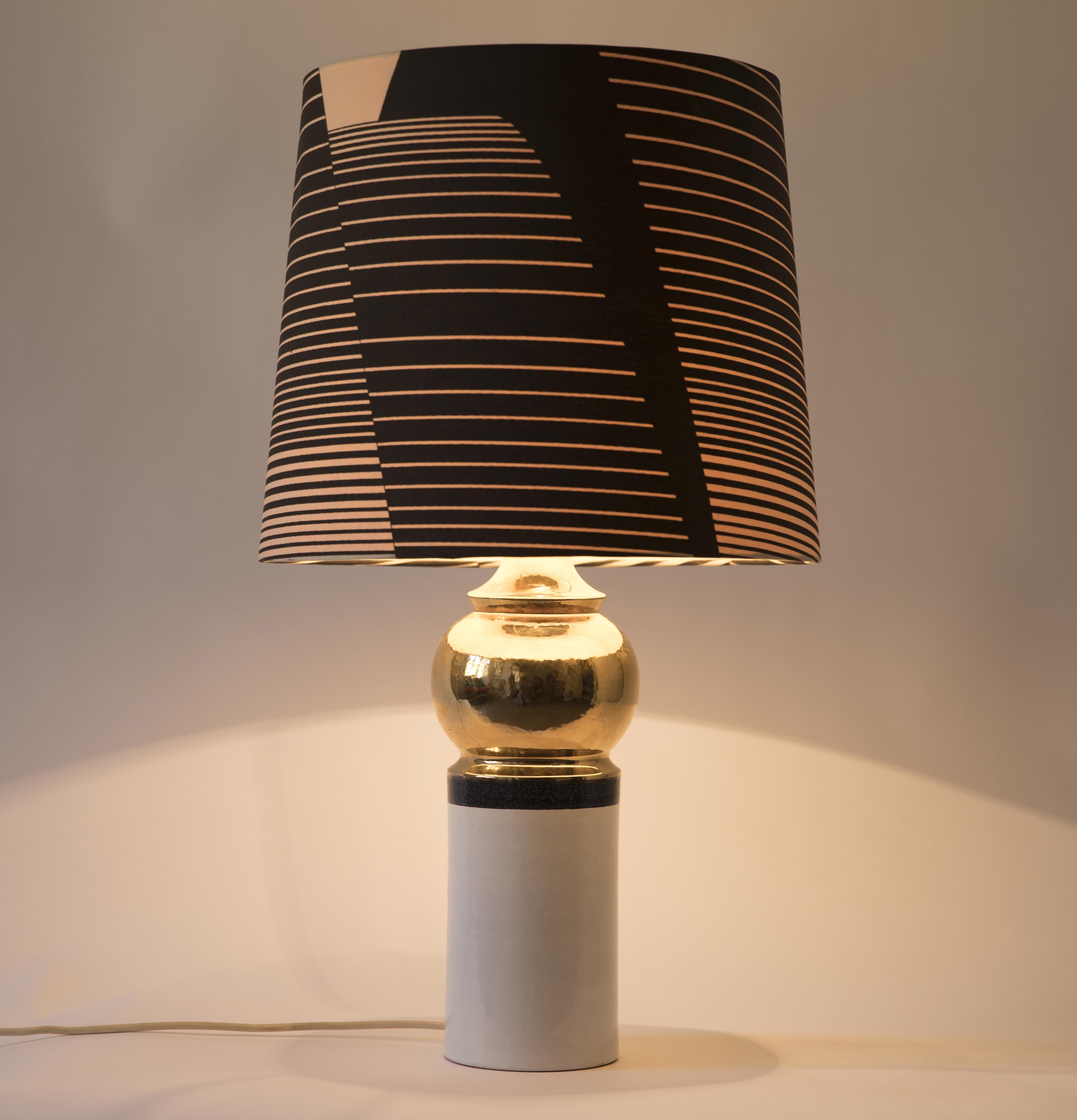 Elegant glazed ceramic table lamp with cylinder shaped base and original shade. In excellent shape and with functional wiring.

Measures: Height 74 cm
Shade diameter 40 cm
Shade height 37 cm
Base diameter 14 cm.
