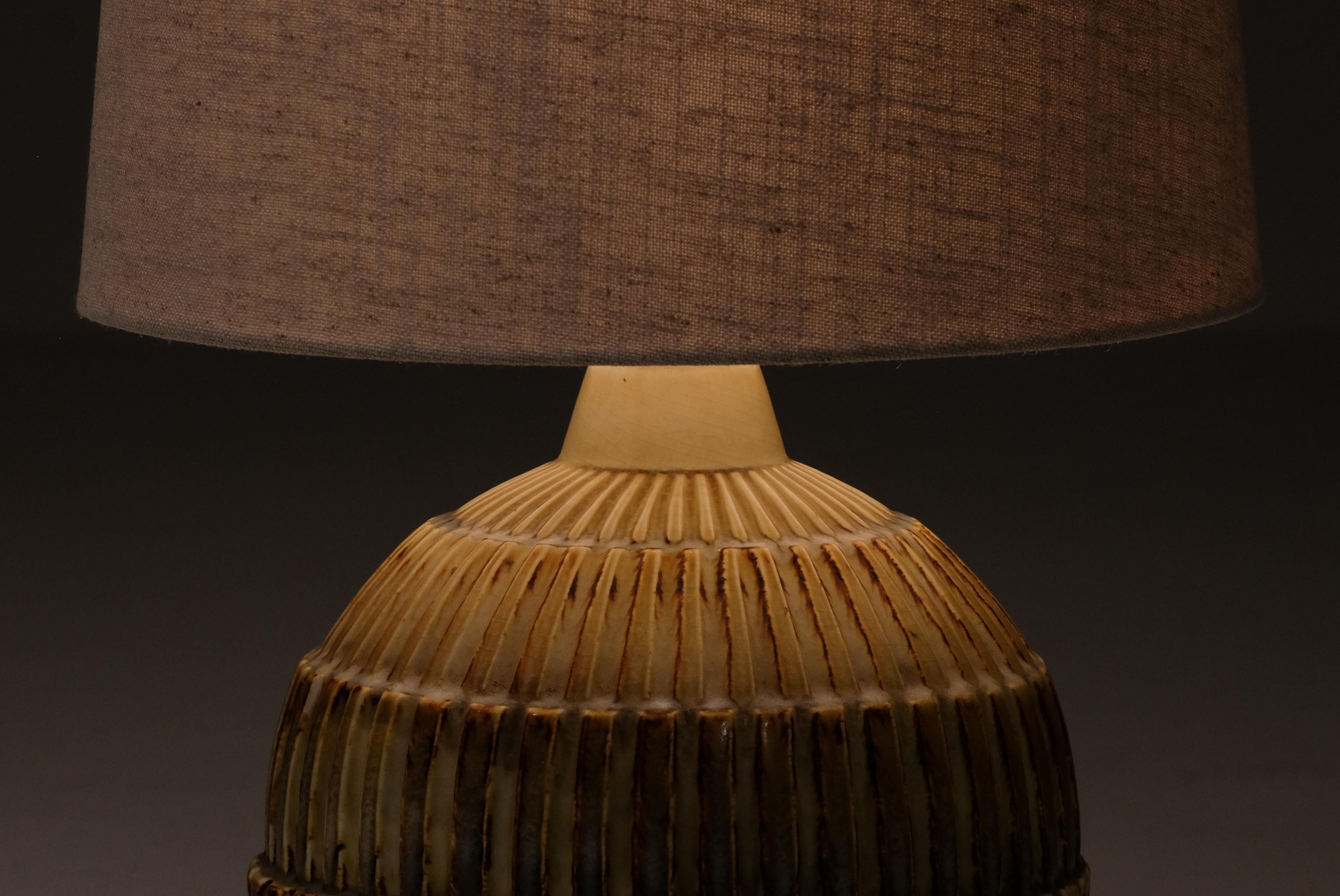 Ceramic table lamp by Gertrud Lonegren in golden glaze and a highly textured surface. 

Measurement (with lampshade)
Diameter: 35 cm
Height: 56 cm

Lonegren studied in Vienna and Stockholm during the 1920s, she worked at Upsala-Ekeby in the