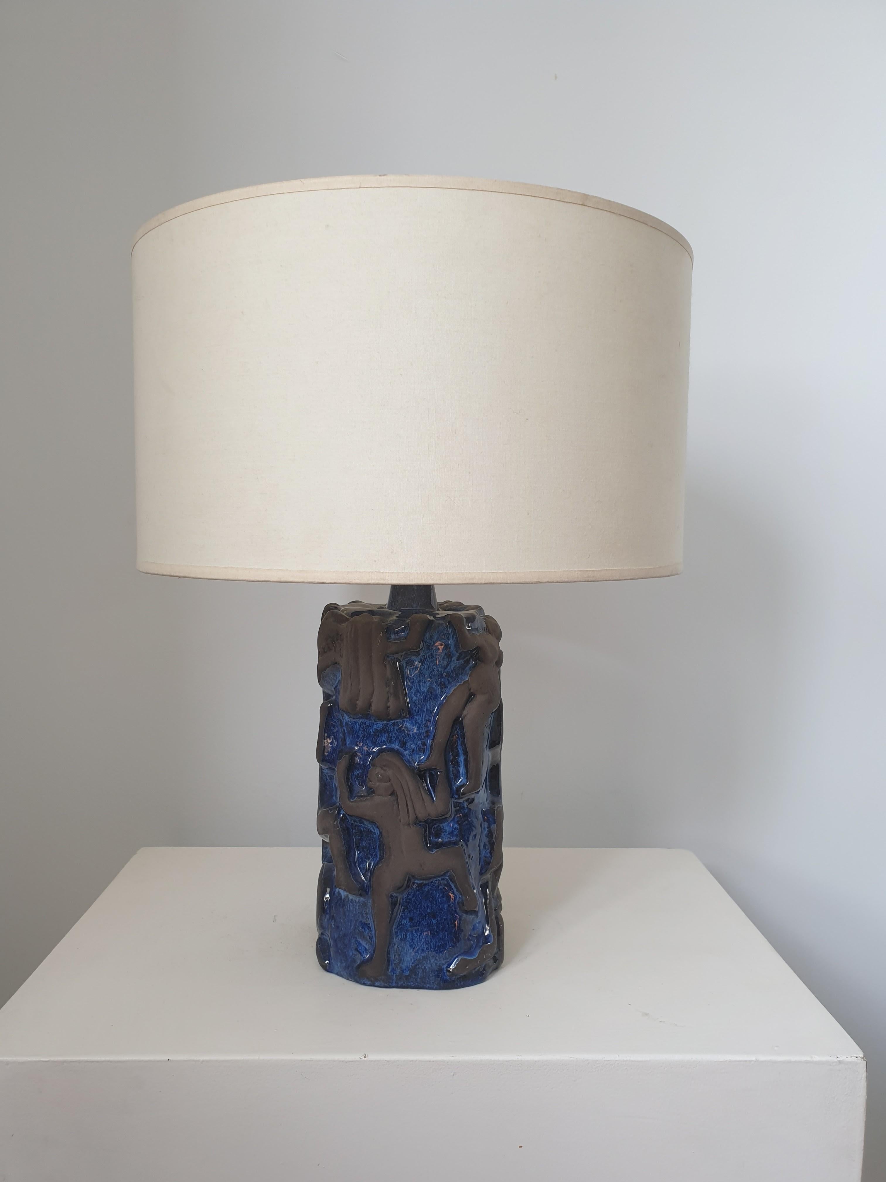 Unusual ceramic table lamp in cobalt blue and brown ceramic. The cobalt blue background has a high glaze and the climbing figures are in brown unglazed ceramic. This beautiful design in high relief depicts naked figures climbing up a cliff face.