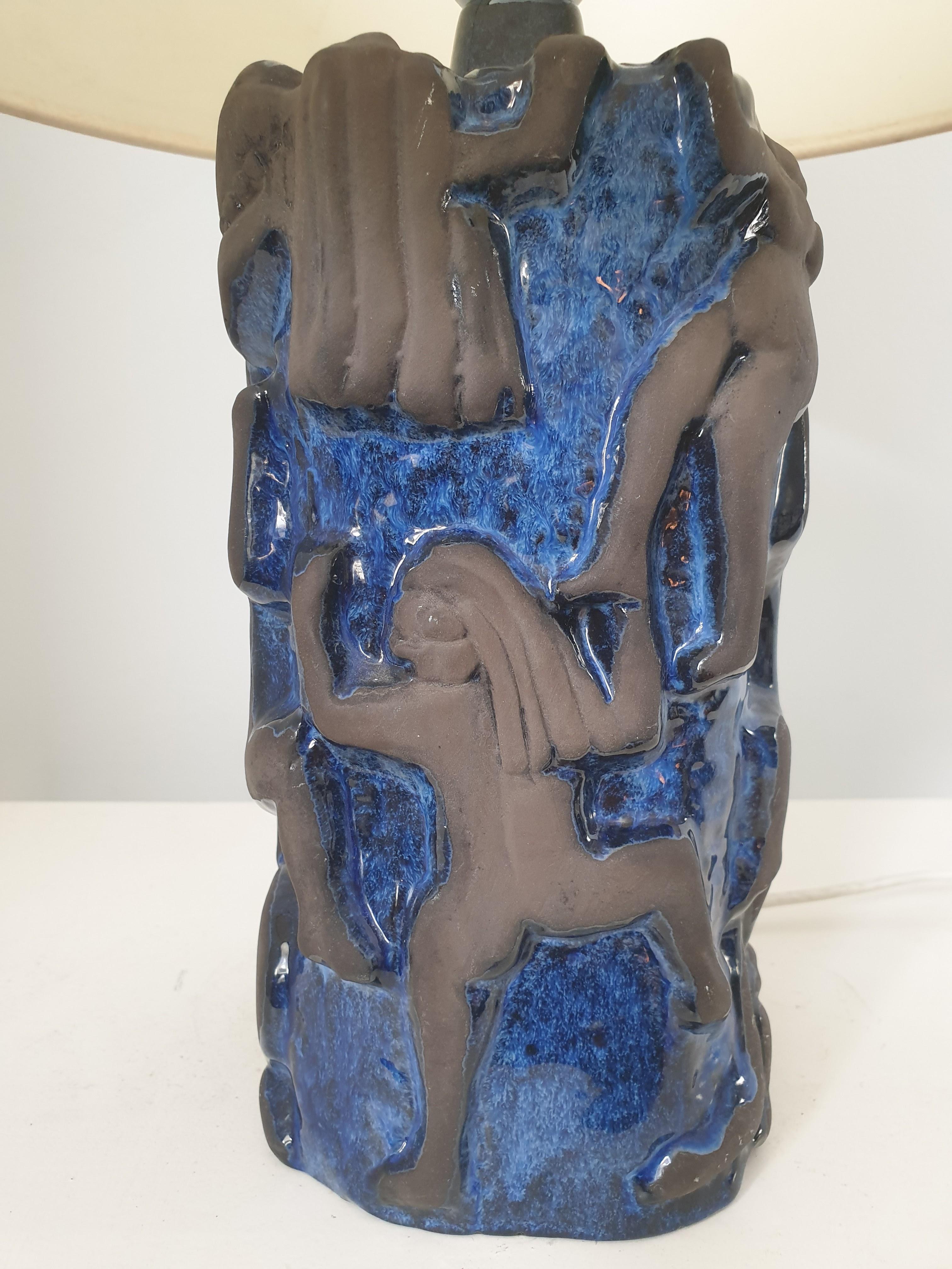 Unusual ceramic table lamp in cobalt blue and brown ceramic. The cobalt blue background has a high glaze and the climbing figures are in brown unglazed ceramic. This beautiful design in high relief depicts naked figures climbing up a cliff face.