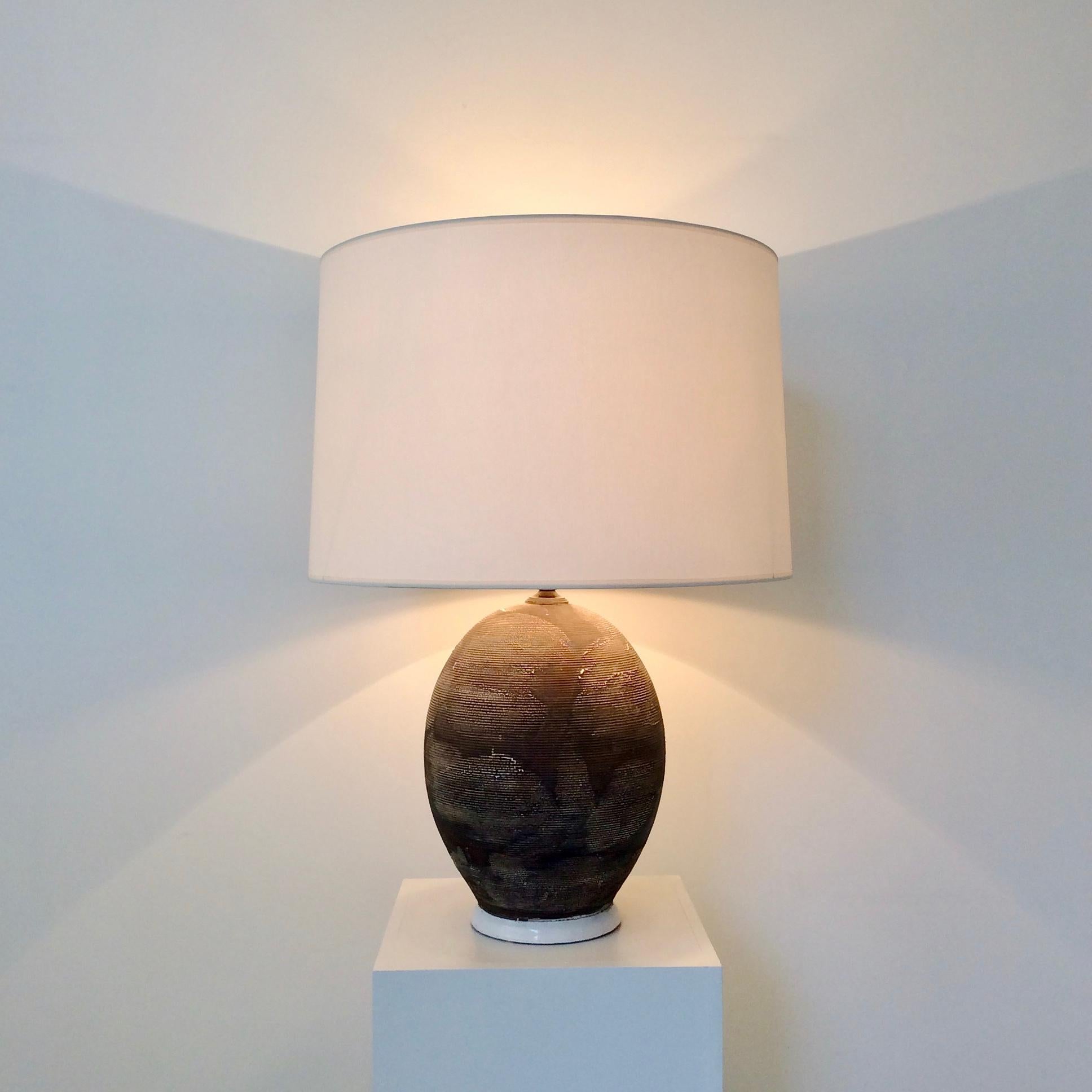 Ceramic table lamp, circa 1940, France.
Brown and white textured, enameled ceramic.
New white fabric shade.
3 B22 bulbs of 40 W.
Dimensions: 63 cm H, diameter of the base 15 cm , diameter of the shade 46 cm.
Good condition.
  