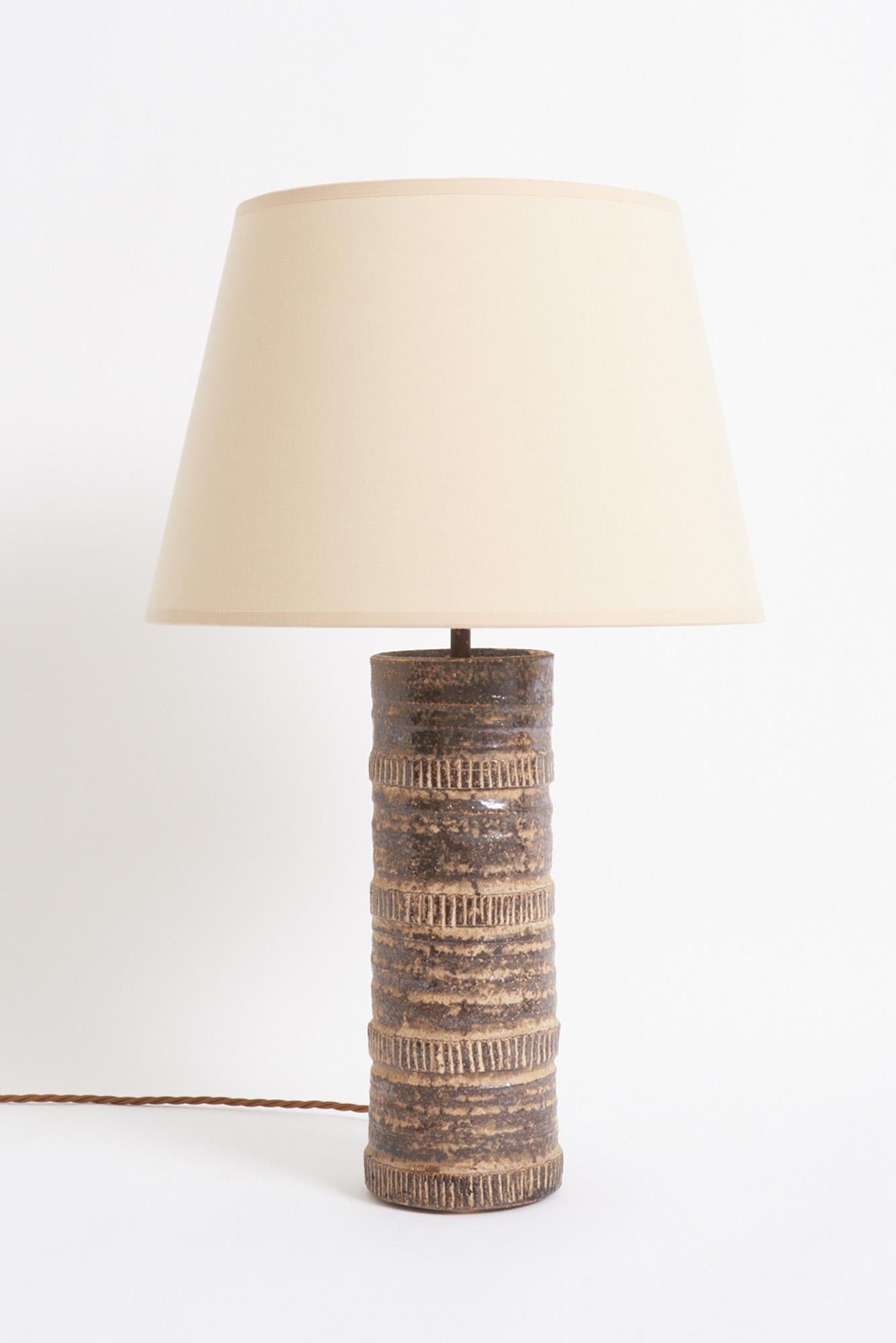 A textured ceramic table lamp
France, mid 20th Century
With the shade: 58 cm high by 35.5 cm diameter 
Lamp base only: 39.5 cm high by 11 cm diameter