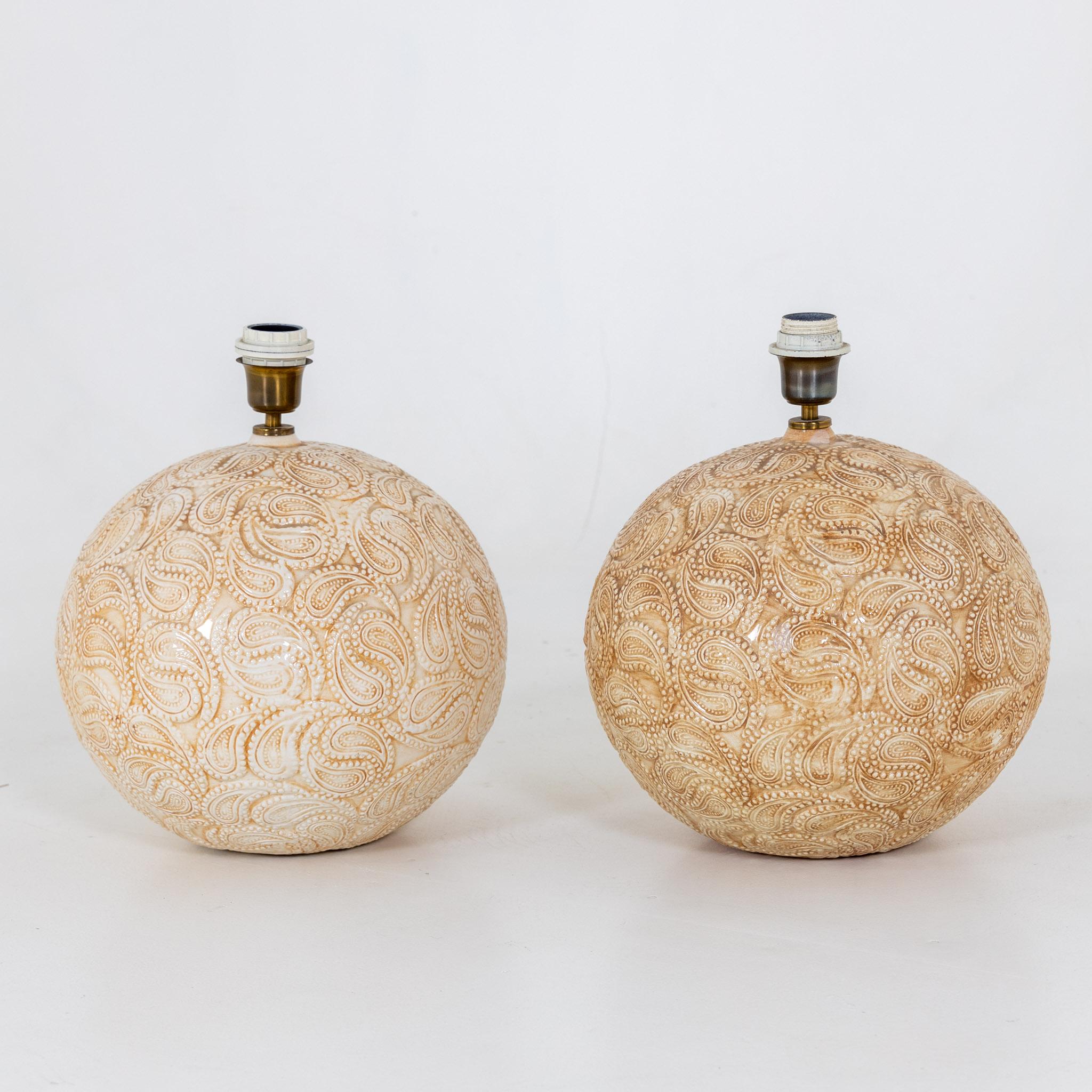 Paar Tischlampen mit kugelförmigen Körpern aus glasierter Keramik und Paisleymuster an der Wand.