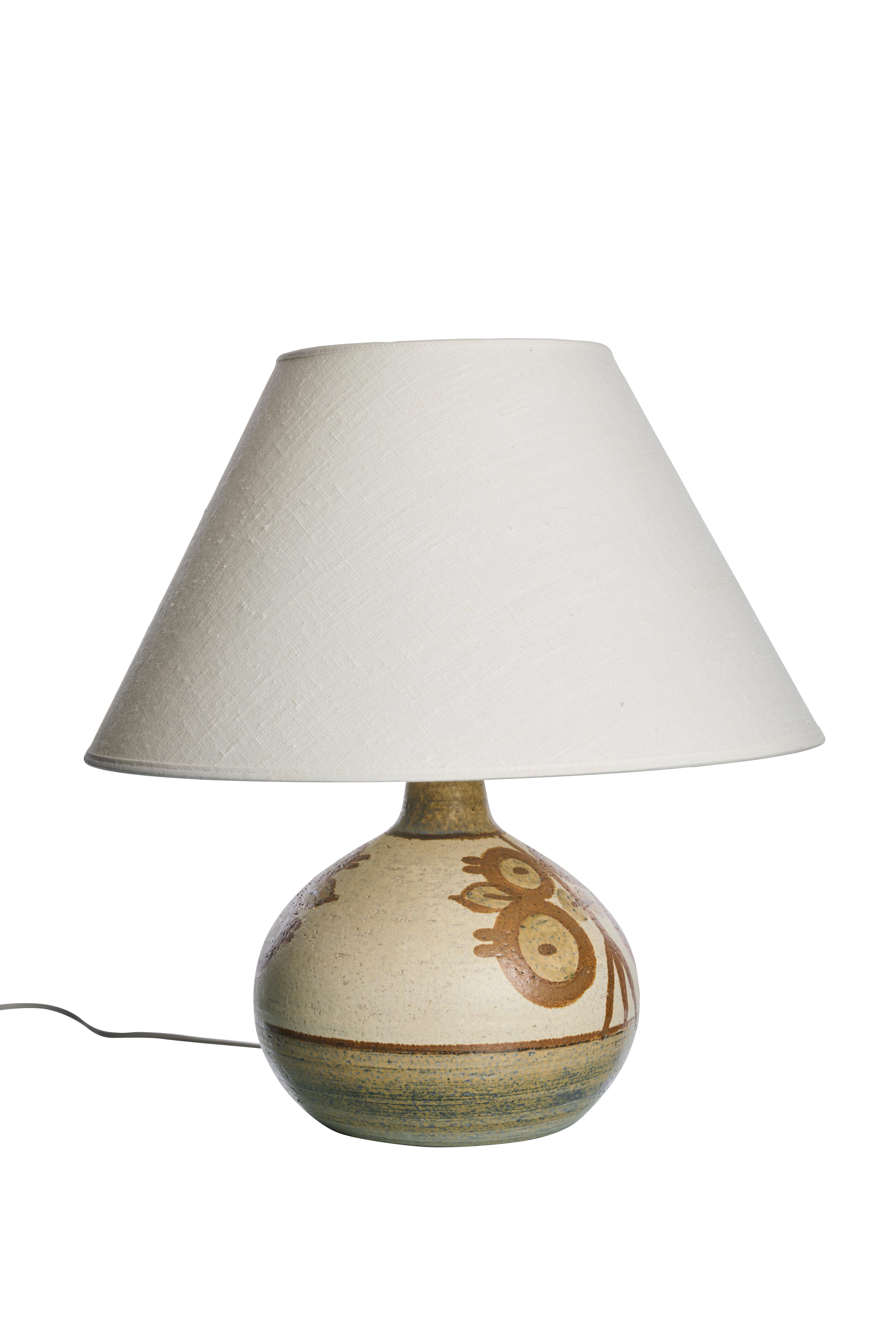 This is a vintage ceramic table lamp, designed by Noomi Backhausen for Søholm in Denmark during the 1960s. The lamp features a round, bulbous base made of ceramic with a hand-painted design. The design includes abstract motifs in earthy tones,