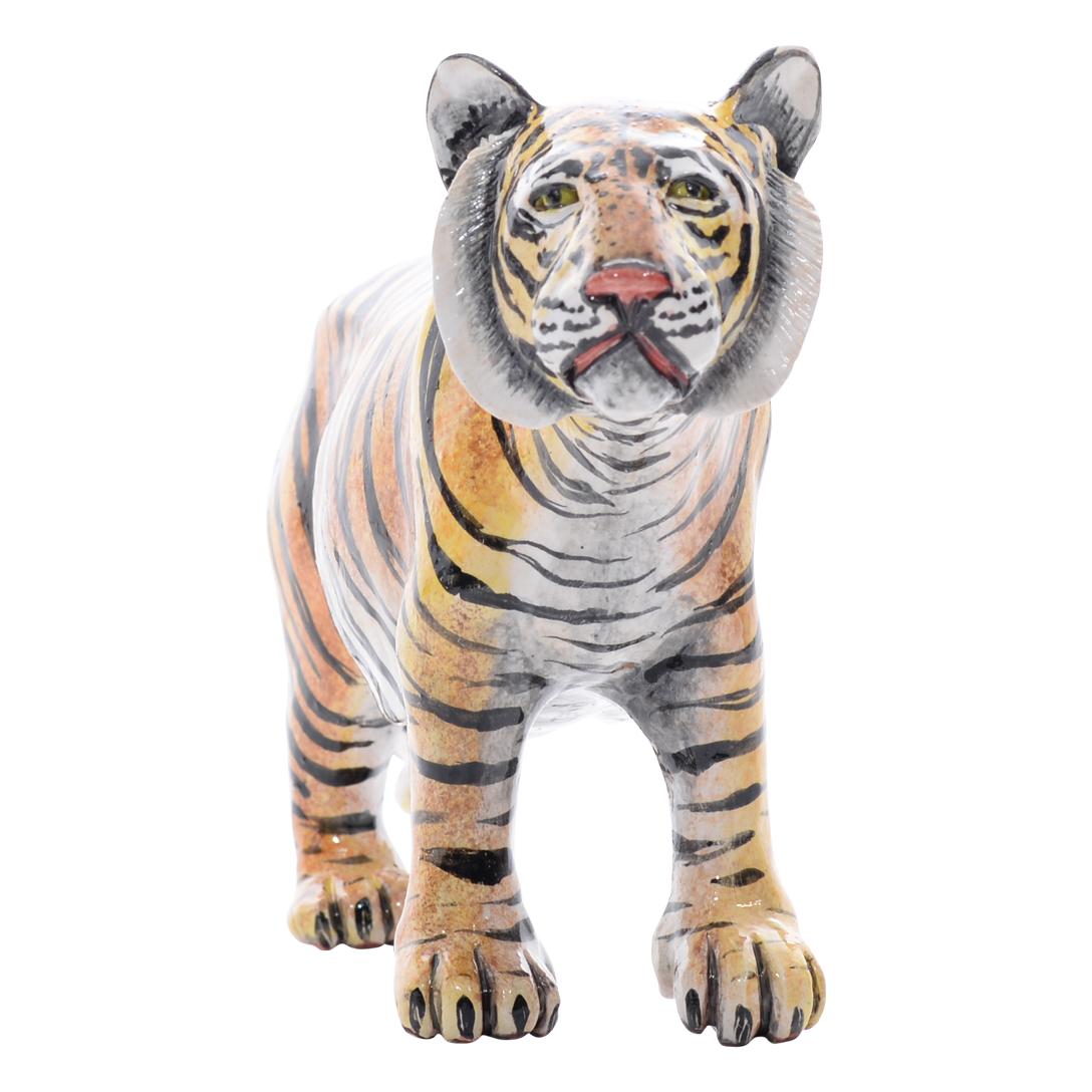 Crafted by Bernard and painted by Virginia at Imvelo Natural Art in South Africa, this ceramic Tiger sculpture stands 6 inches high, 12 inches long, and 3 inches wide. The sculpture portrays the tiger in a standing pose, capturing its majestic