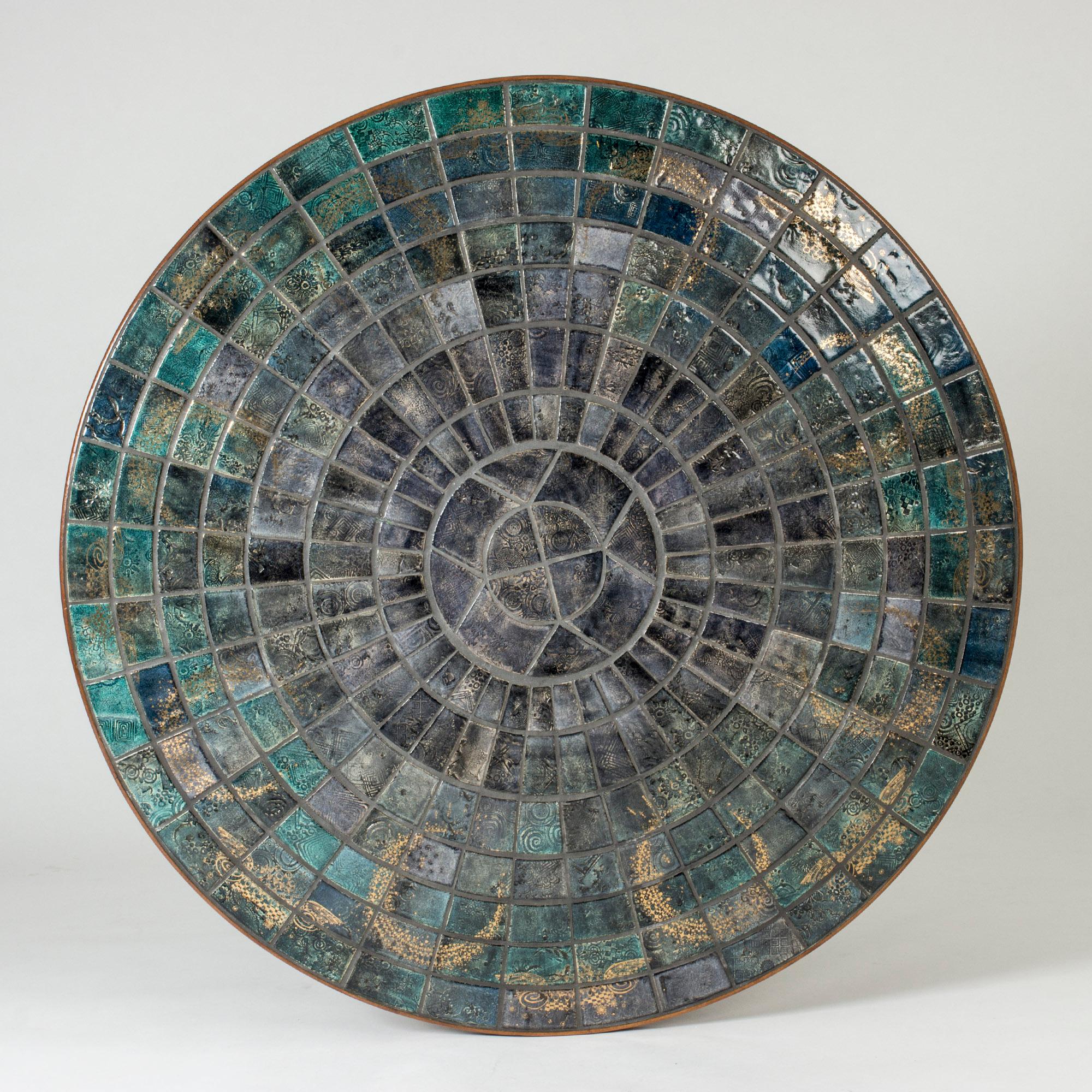 Étonnante table basse unique en grès et en teck de l'artiste acclamé Bjørn Wiinblad. De magnifiques carreaux de couleur variant entre le gris, le bleu et le vert avec un décor jaune doré sont placés sur le plateau de la table. Motif sophistiqué de