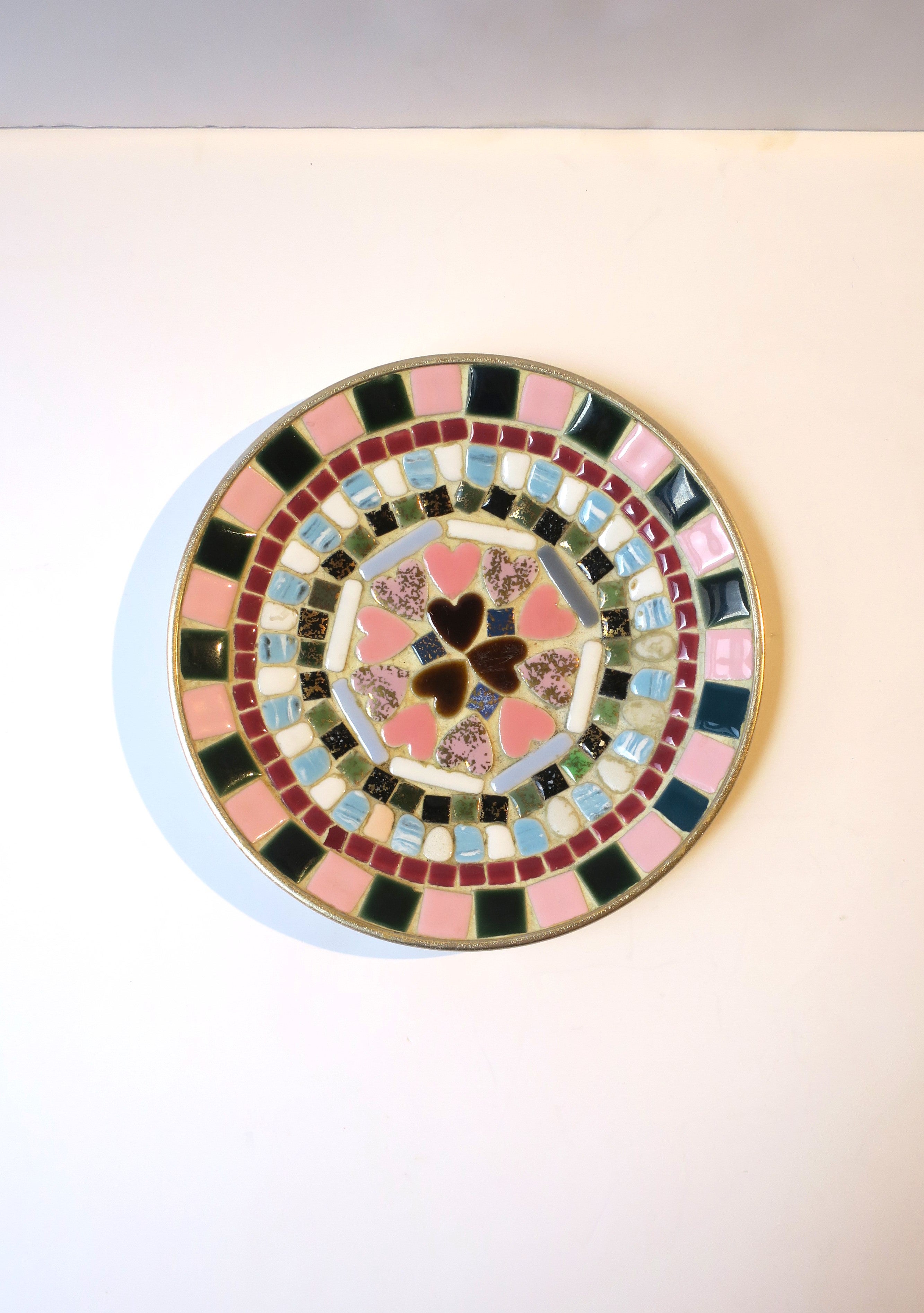 A ceramic tile mosaic dish catchall or vide-poche with pink hearts, circa mid-20th century, 1960s, USA. Dish is round; designed with square and rectangular tiles and a cluster of heart shaped tiles at centre. Tile colors include pastel pinks, light