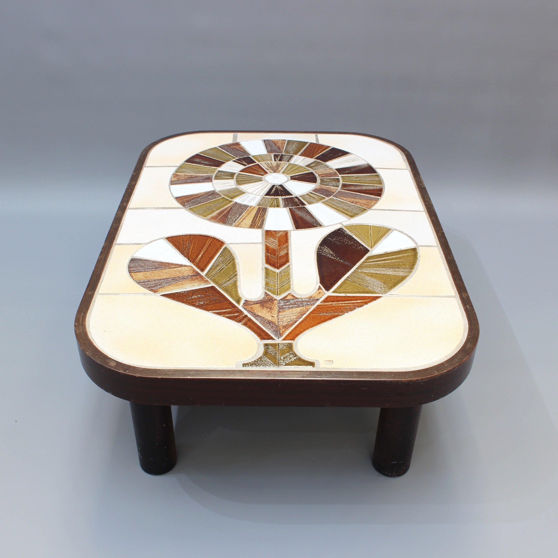 Ceramic tiled coffee table by Roger Capron (circa 1970s). A large, stylised flower is the centre piece of this original work by famed Vallauris ceramicist, Roger Capron (1922 - 2006). The tiles are surrounded by the table's dark wooden frame with