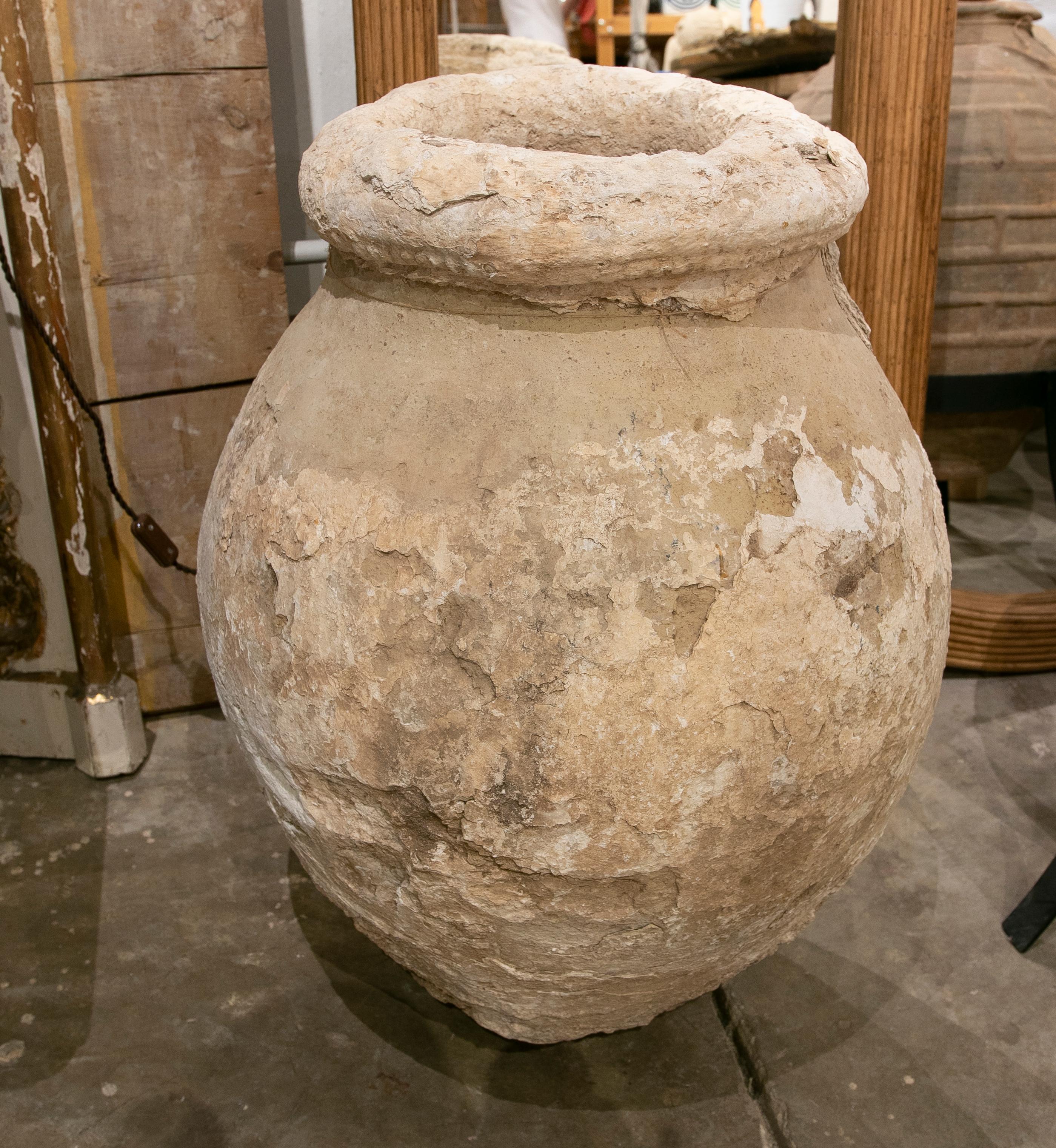 Ceramic tinaja covered with various layers of lime.