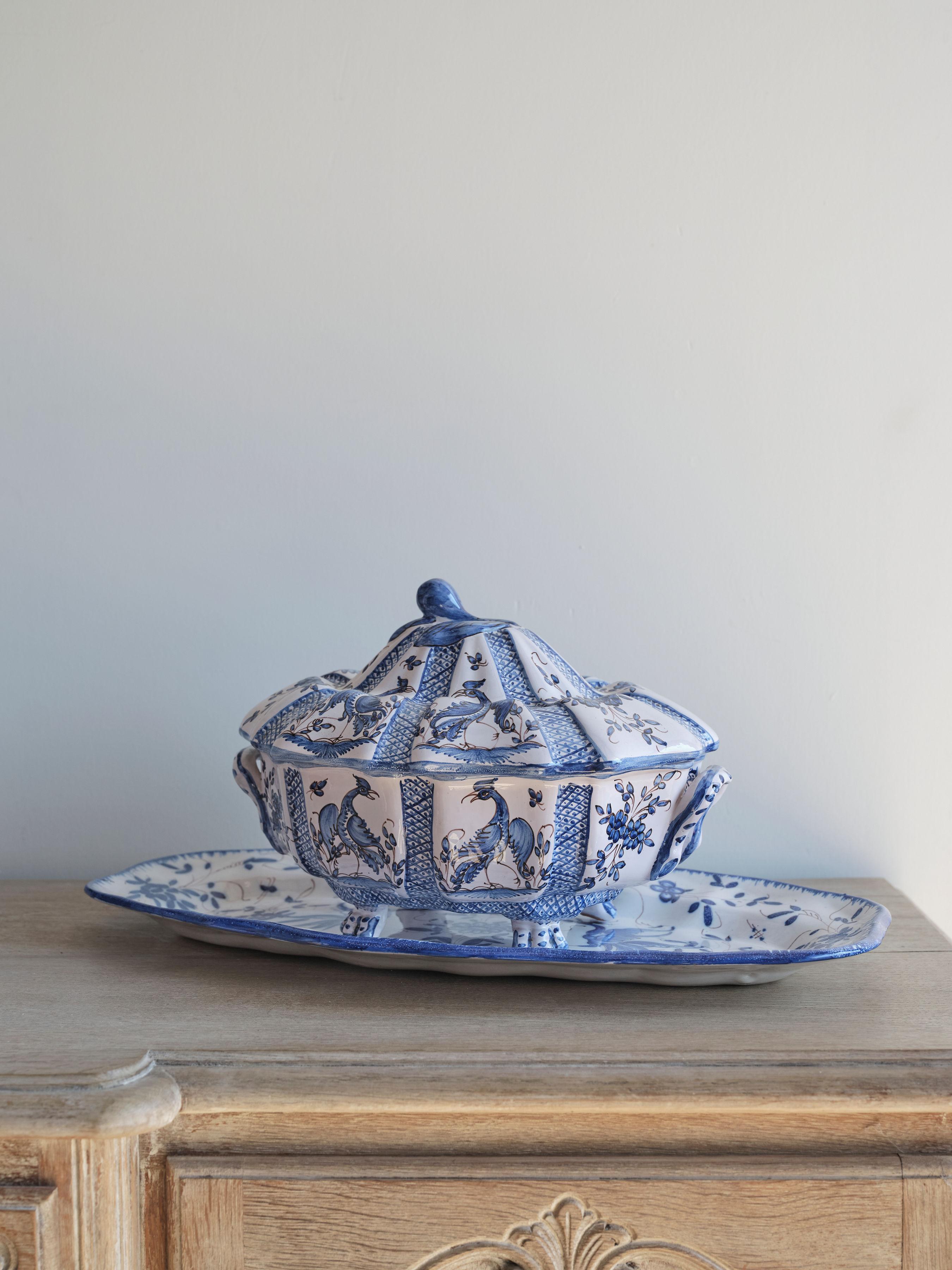 This lovely tureen and tray feature a Delft style of blue and white floral. There are also several peacocks featured on both the tray and tureen. The tureen has a handle on each side. These pieces were created in 1960, yet they are both in pristine