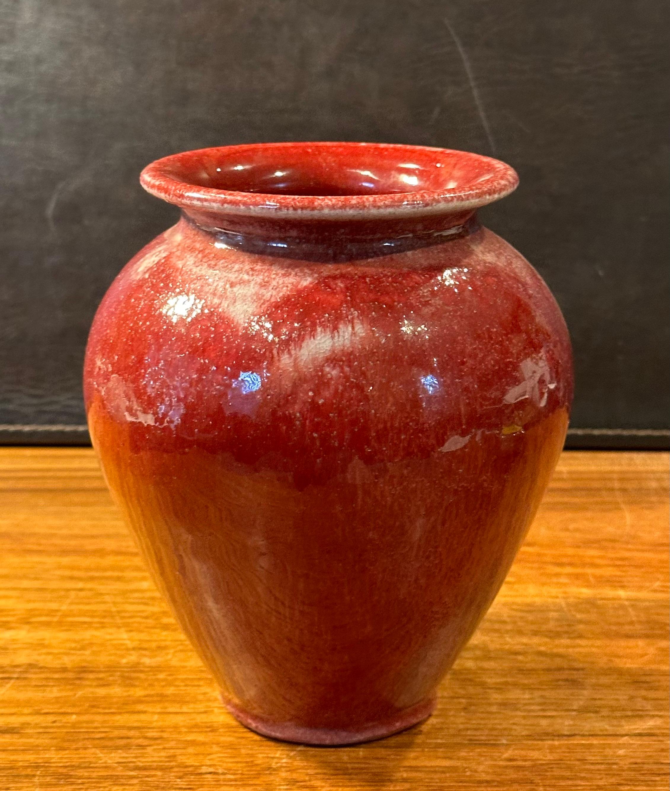 A vibrant cabernet red ceramic vase by noted San Diego potter Alex Long, circa 2004.  The hand thrown vase is in great vintage condition with no chips or cracks and it measures 6