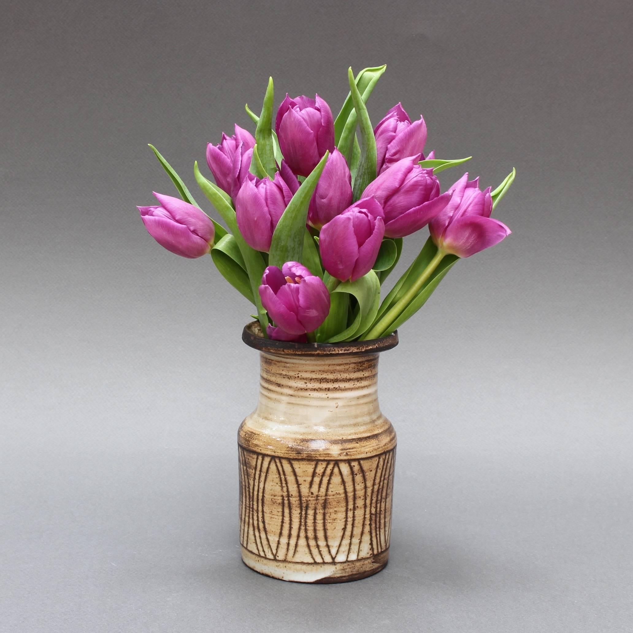 This petite midcentury ceramic vase (circa 1960s) is done in Pouchain's trademark style with muted brown horizontal lines above a frieze with oval motif over a beige and darker glaze. The hallmark etching appears on the vase bottom, 'Atelier