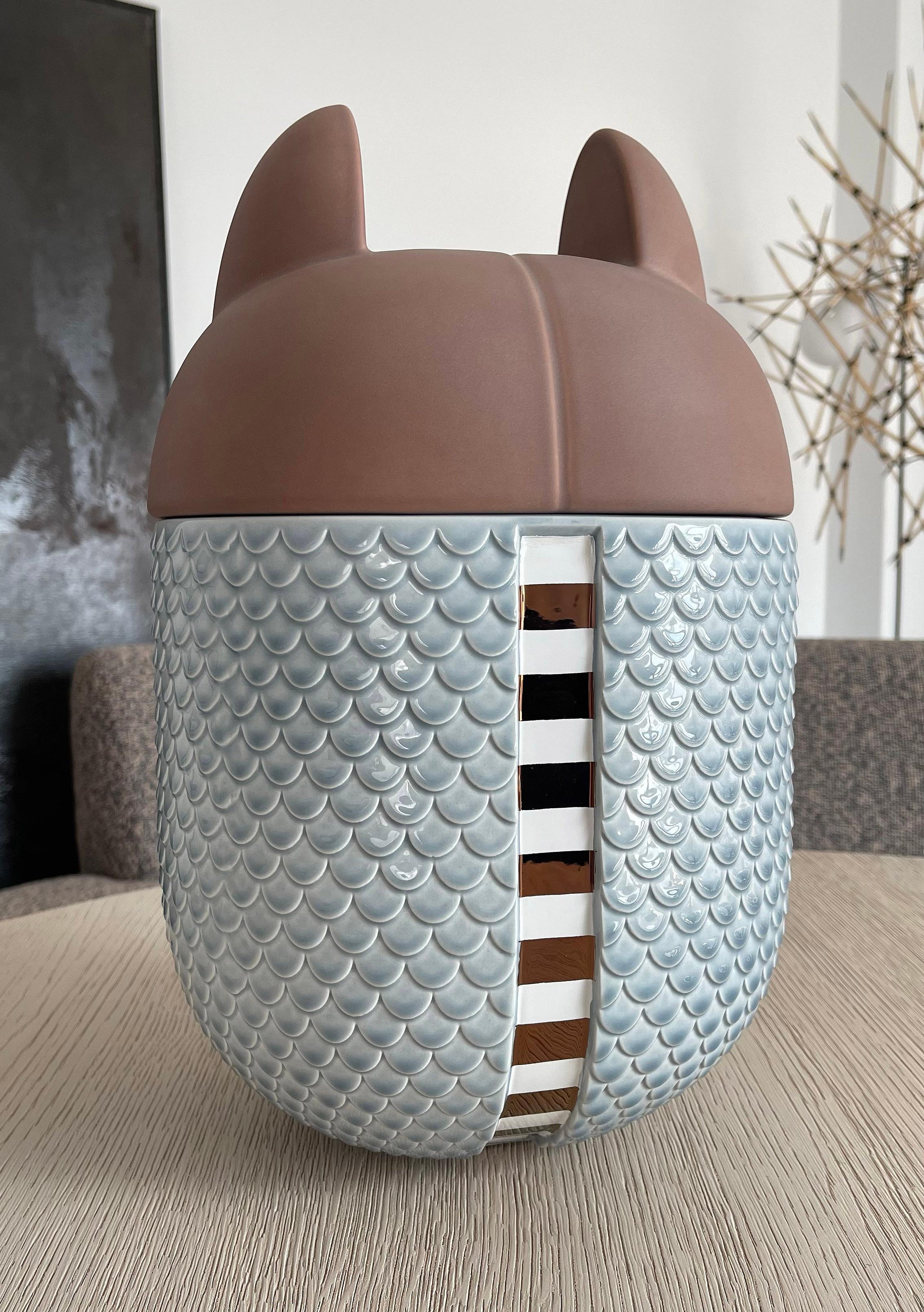 Vase / Behälter aus Keramik - Animalità Khepri von Elena Salmistraro für Bosa

Khepri, entworfen von Elena Salmistraro für Bosa, ist ein gürteltierförmiges Gefäß aus Keramik, das mit Edelmetallen angereichert ist und dessen Schale eine symbolische