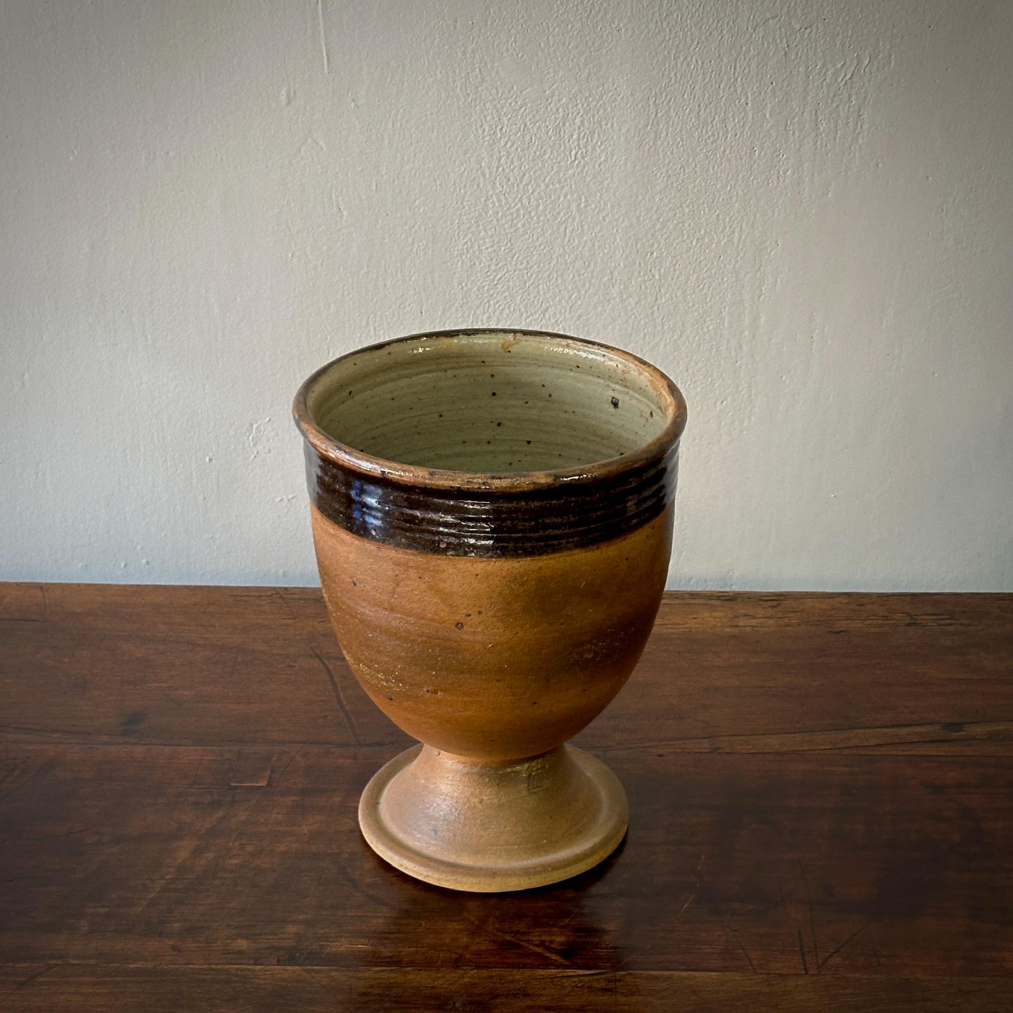 Questo vaso in ceramica francese mette in mostra l'affinità dell'epoca con i toni della terra, con una miscela armoniosa di bande smaltate marroni opache e lucide. Il suo design emana una raffinata rusticità, rendendolo un'aggiunta di spicco a