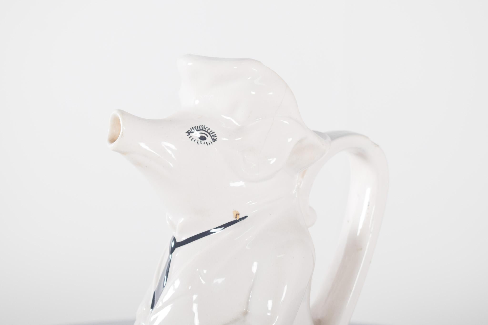 Ceramic jug from Águeda. Figure of a human with a pig's head, in glazed white, giving a shiny, smooth finish to the touch. The jug depicts a pig dressed in a suit and tie, sitting elegantly. The details of the face include expressive, black-painted