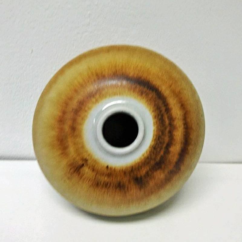 Round and special decorative handmade ceramic vase which looks like an onion. Matt finish with silky surface to touch. Yellow/beige/brown mixed colors. Measures: 15 cm H, 12 cm D at the bottom, cm opening on the top of the vase. Signed Höganäs,