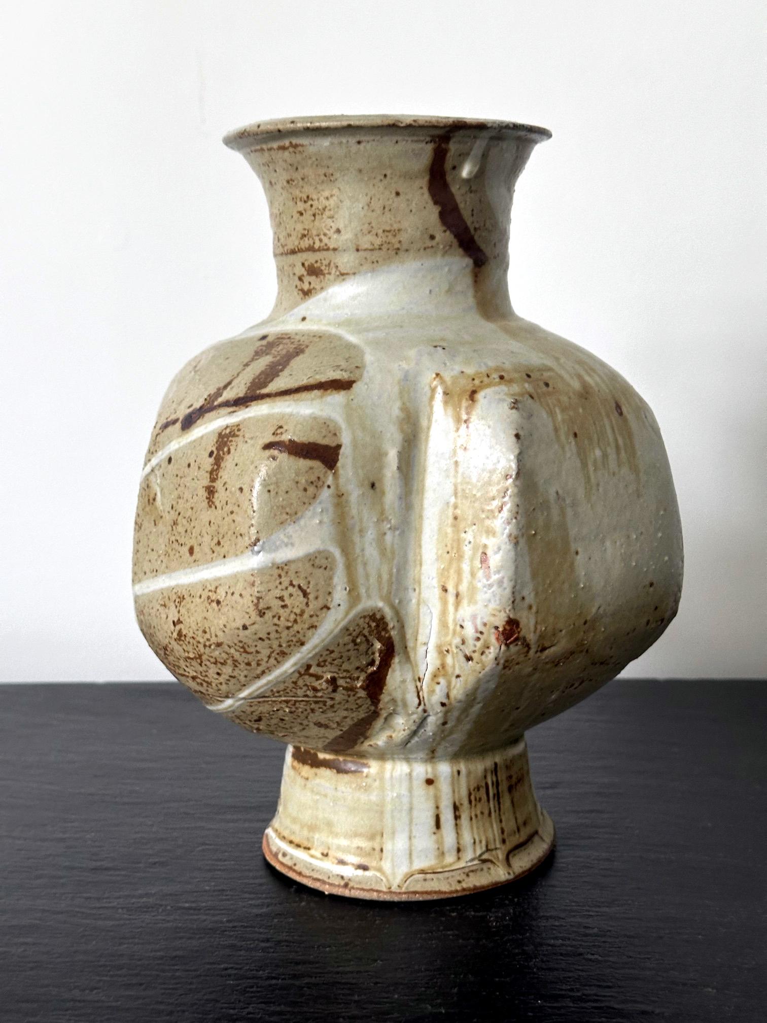 Made by Japanese ceramic artist Makoto Yabe (1947-2005), this stoneware vase features a globular body supported by a round pedestal foot. A similarly shaped neck extends to a rimmed mouth opening. Robust in form with thick wall, the vase is noted