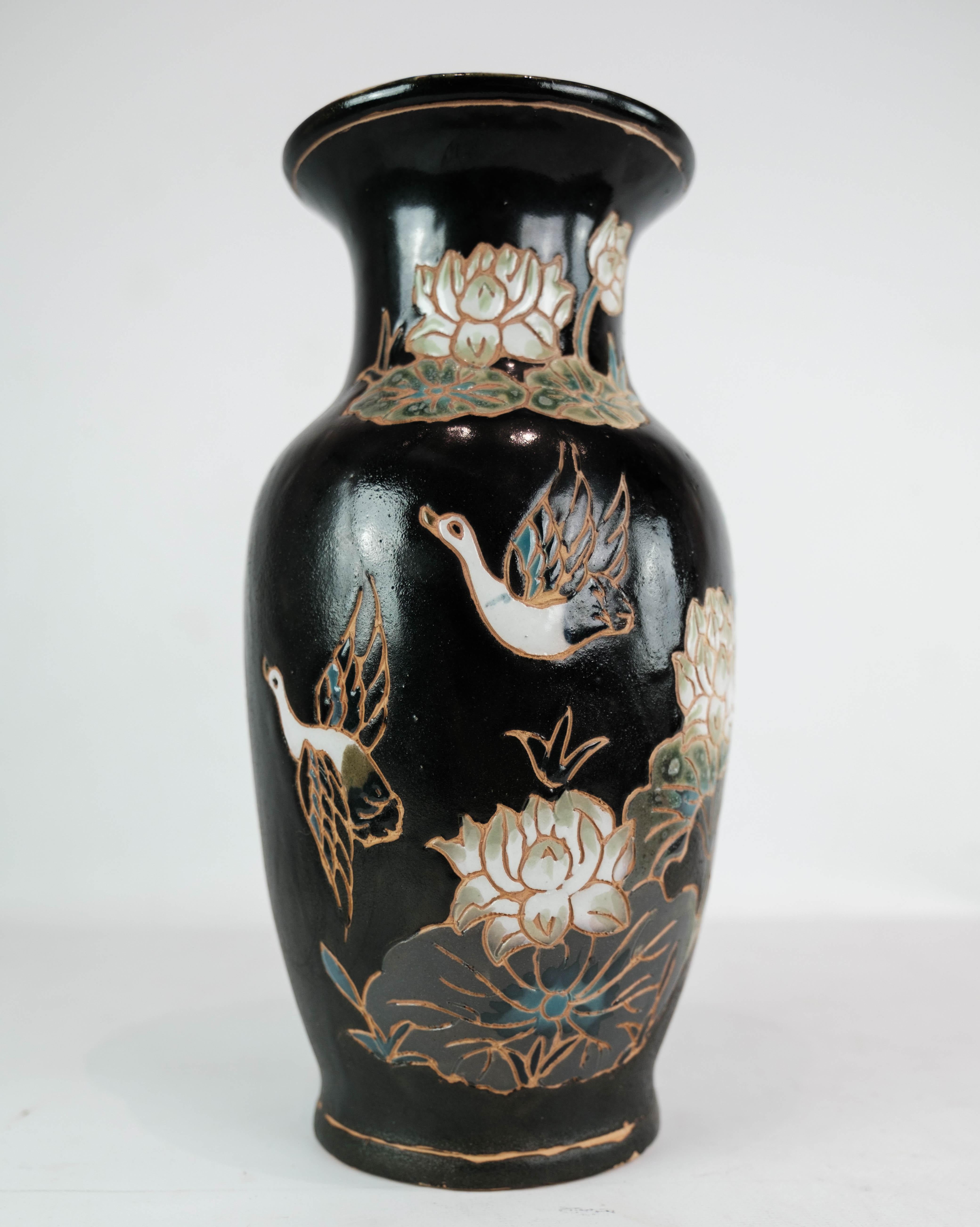 This ceramic vase boasts a sleek black glaze adorned with charming floral motifs, capturing the essence of vintage elegance. Crafted in the 1960s, it stands as a testament to the enduring appeal of mid-century design.

In excellent vintage