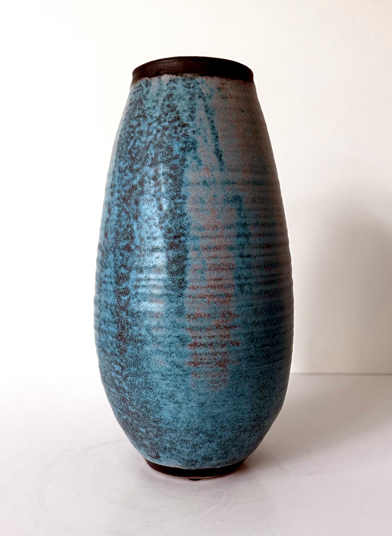Un vaso alto in ceramica realizzato dal ceramista americano Otto Heino (1915-2009) nell'ultimo anno della sua vita nel suo studio di Ojai, California, nel 1999. Realizzato con linee concentriche intenzionali, la superficie del vaso è ricoperta da